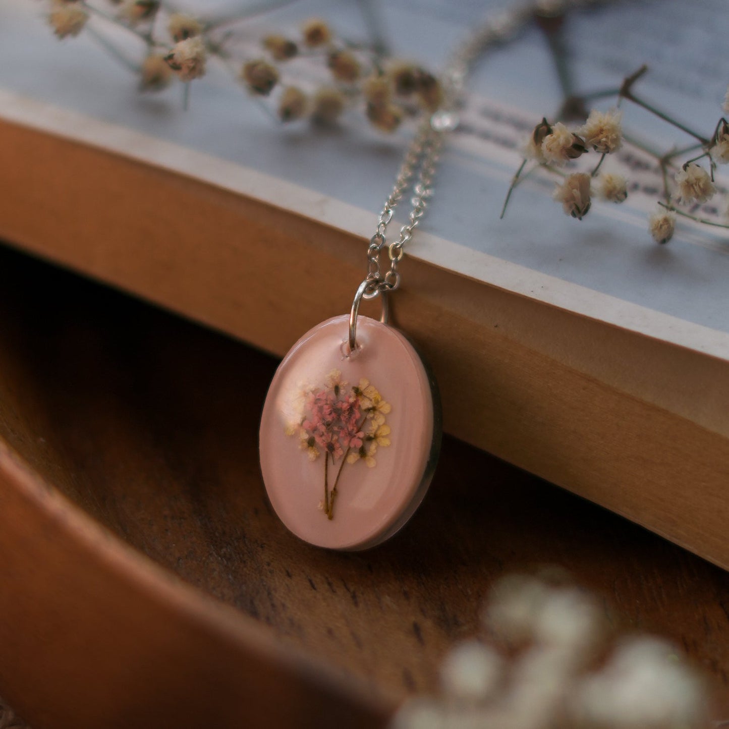 A collection of handmade resin art pendants, showcasing intricate floral designs preserved in clear resin, attached to delicate necklaces.