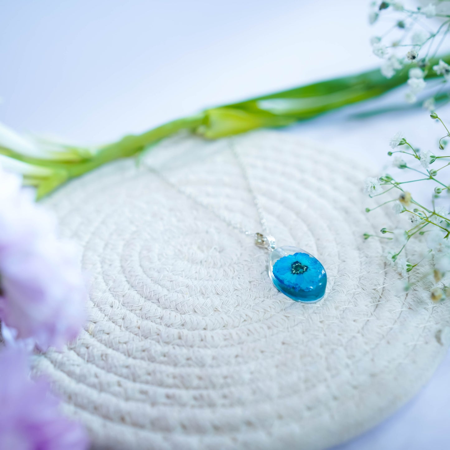 A collection of handmade resin art pendants, showcasing intricate floral designs preserved in clear resin, attached to delicate necklaces.