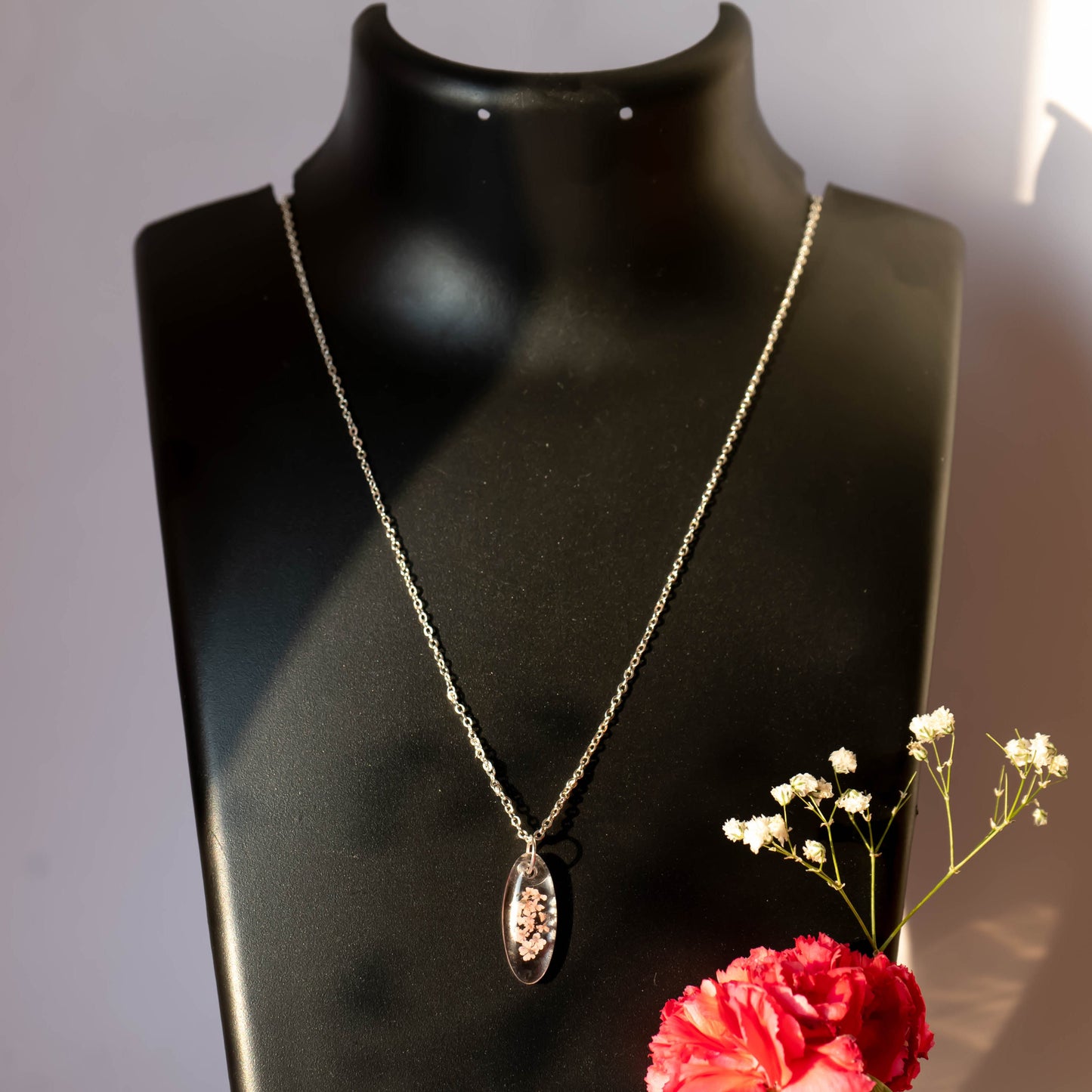 A collection of handmade resin art pendants, showcasing intricate floral designs preserved in clear resin, attached to delicate necklaces.