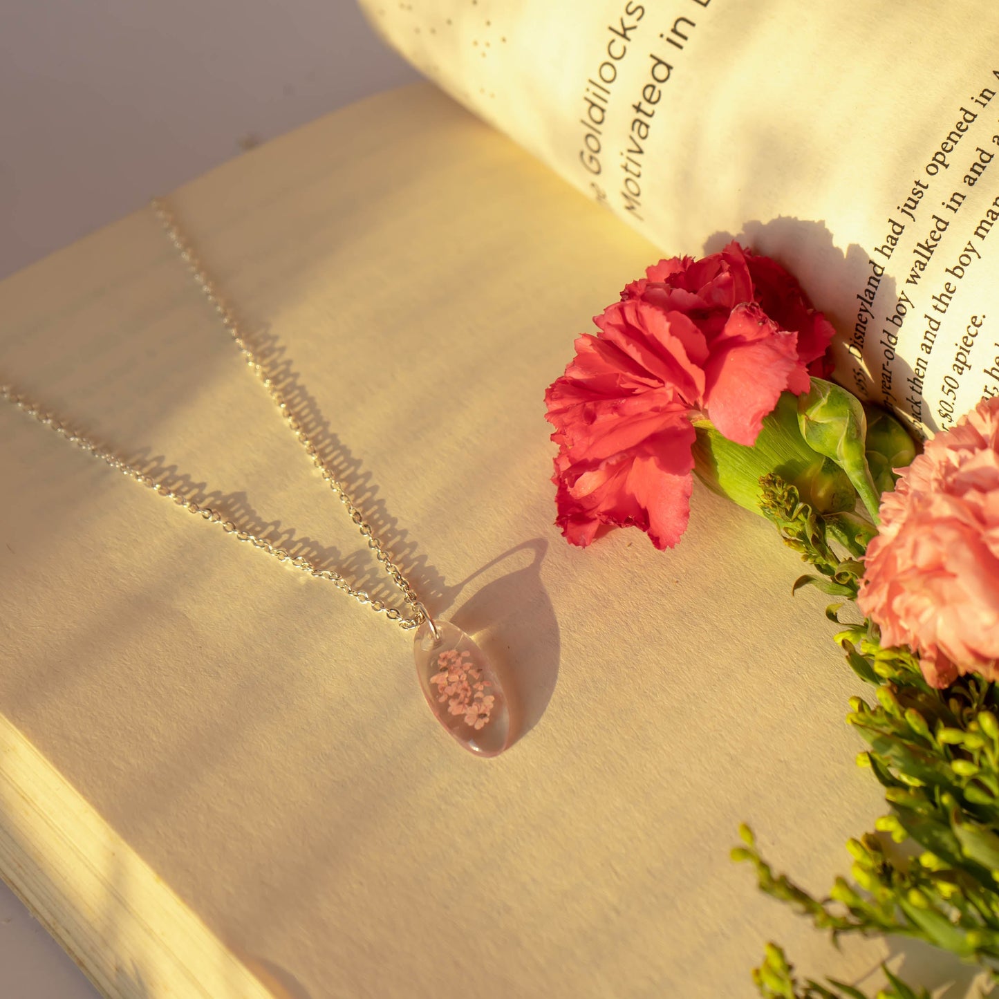 A collection of handmade resin art pendants, showcasing intricate floral designs preserved in clear resin, attached to delicate necklaces.