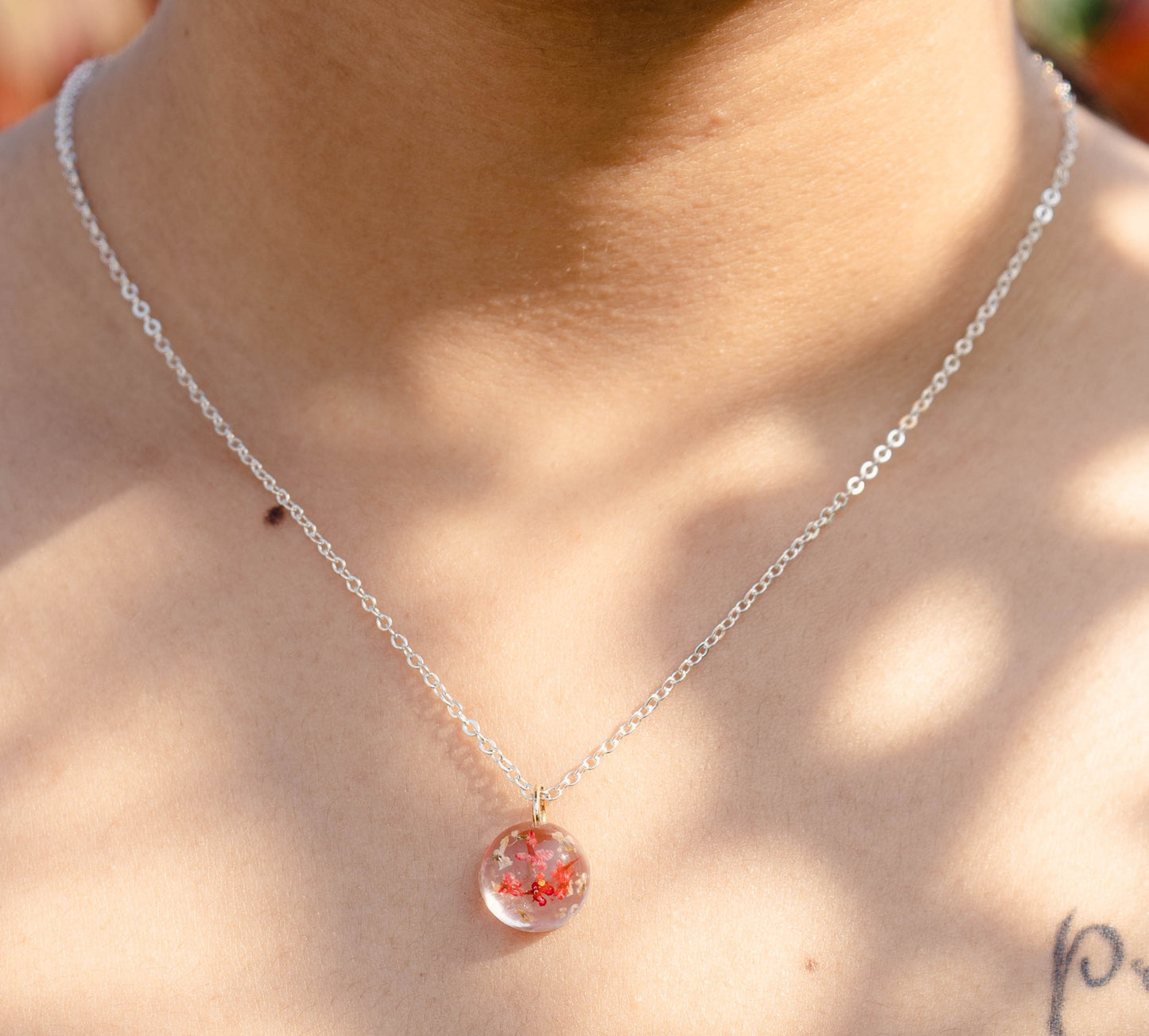 A collection of handmade resin art pendants, showcasing intricate floral designs preserved in clear resin, attached to delicate necklaces.