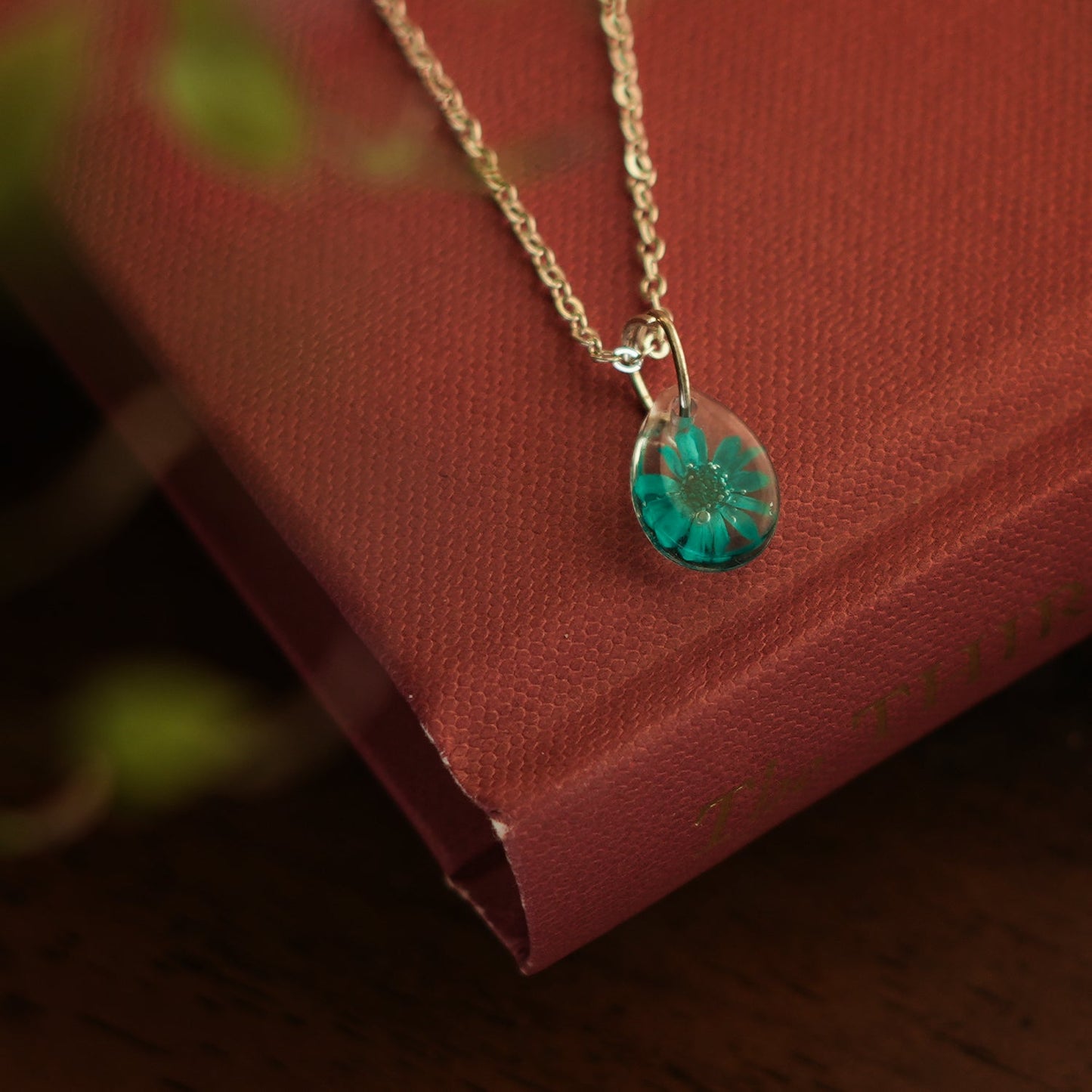 A collection of handmade resin art pendants, showcasing intricate floral designs preserved in clear resin, attached to delicate necklaces.