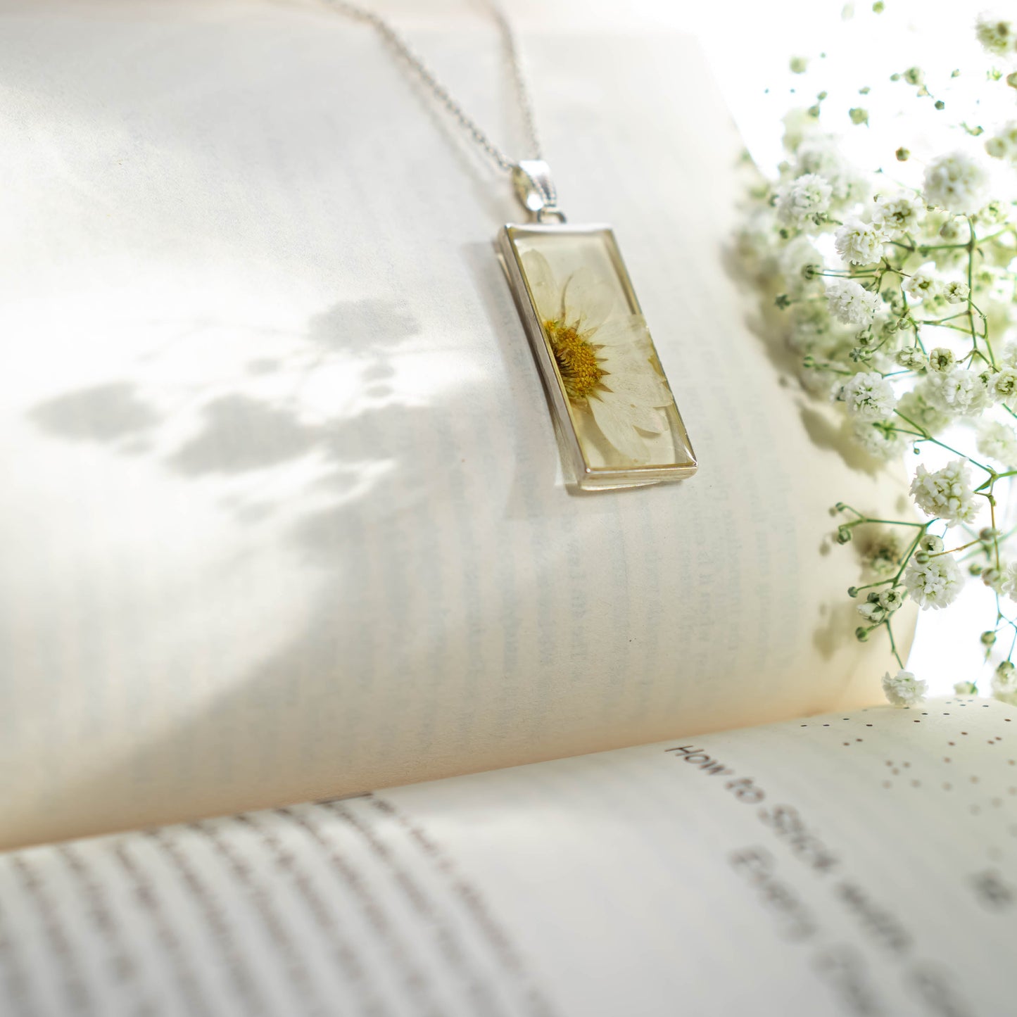 A collection of handmade resin art pendants, showcasing intricate floral designs preserved in clear resin, attached to delicate necklaces.