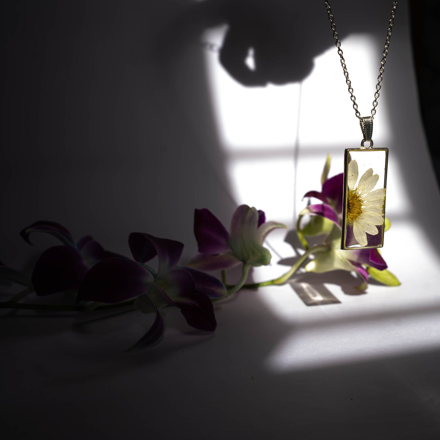 A collection of handmade resin art pendants, showcasing intricate floral designs preserved in clear resin, attached to delicate necklaces.