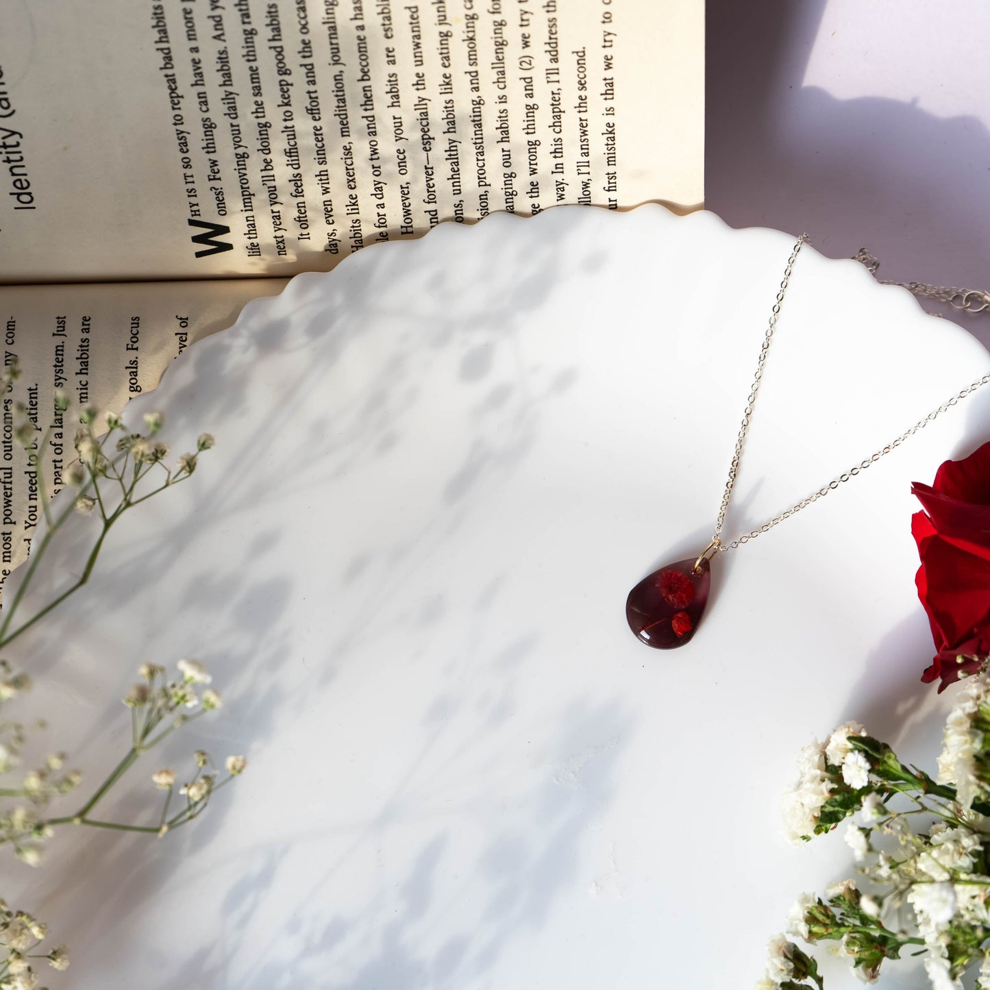 A collection of handmade resin art pendants, showcasing intricate floral designs preserved in clear resin, attached to delicate necklaces.