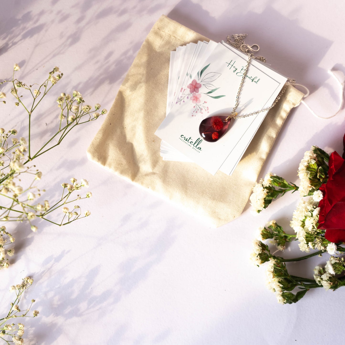 A collection of handmade resin art pendants, showcasing intricate floral designs preserved in clear resin, attached to delicate necklaces.
