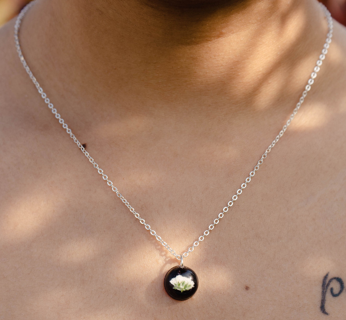 A collection of handmade resin art pendants, showcasing intricate floral designs preserved in clear resin, attached to delicate necklaces.
