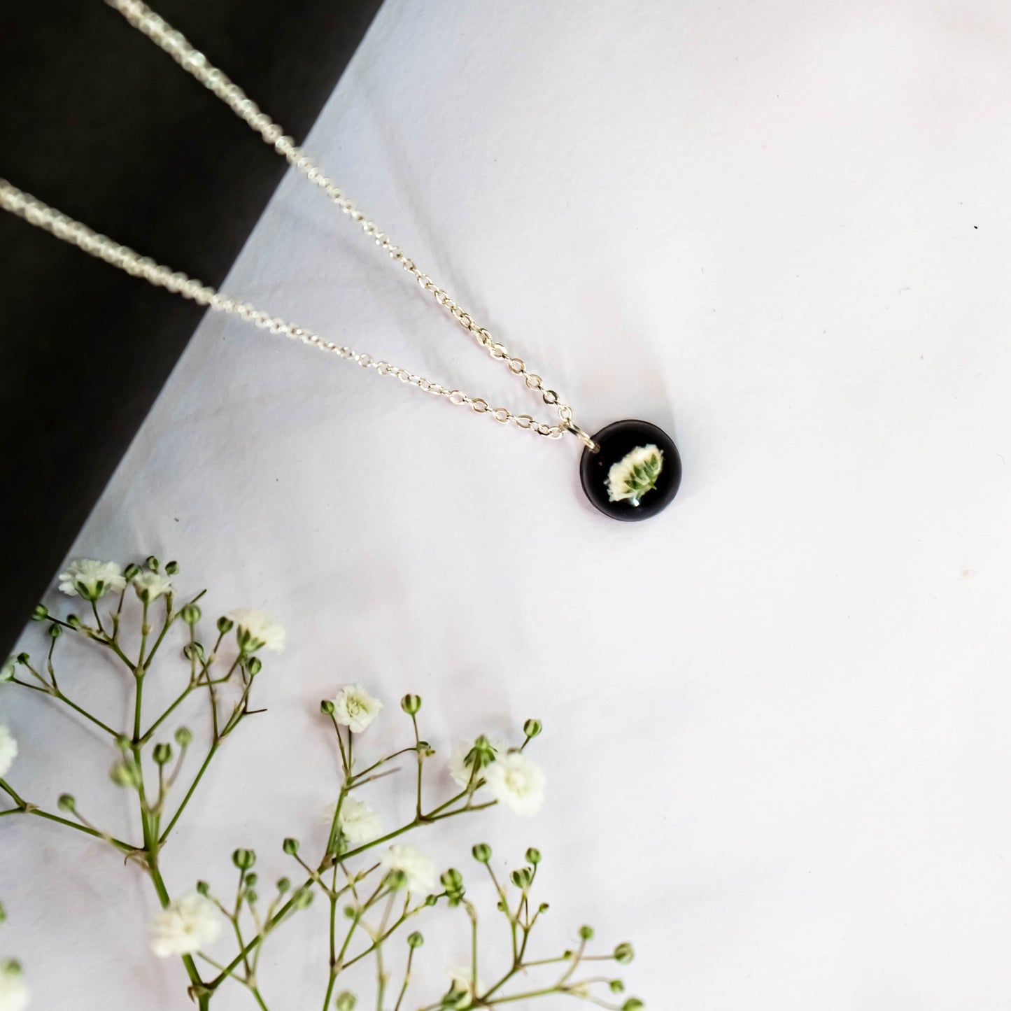 A collection of handmade resin art pendants, showcasing intricate floral designs preserved in clear resin, attached to delicate necklaces.