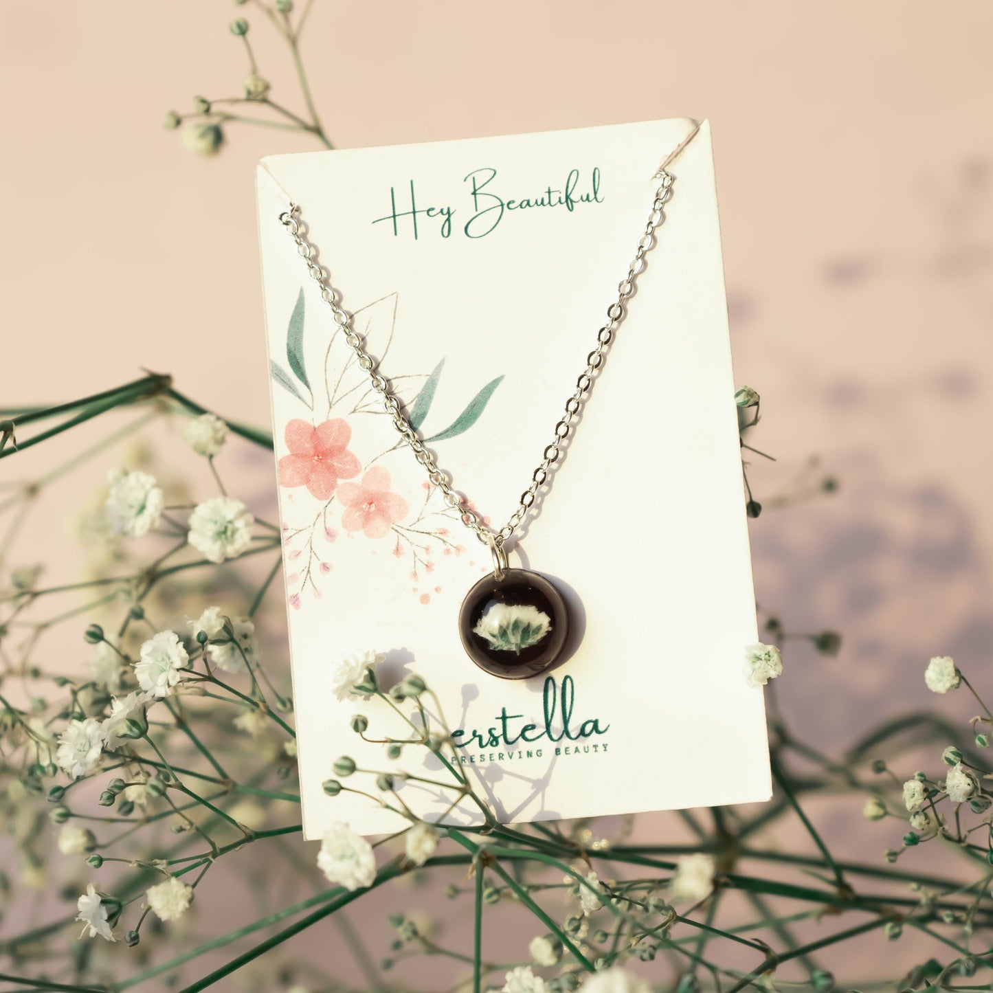 A collection of handmade resin art pendants, showcasing intricate floral designs preserved in clear resin, attached to delicate necklaces.