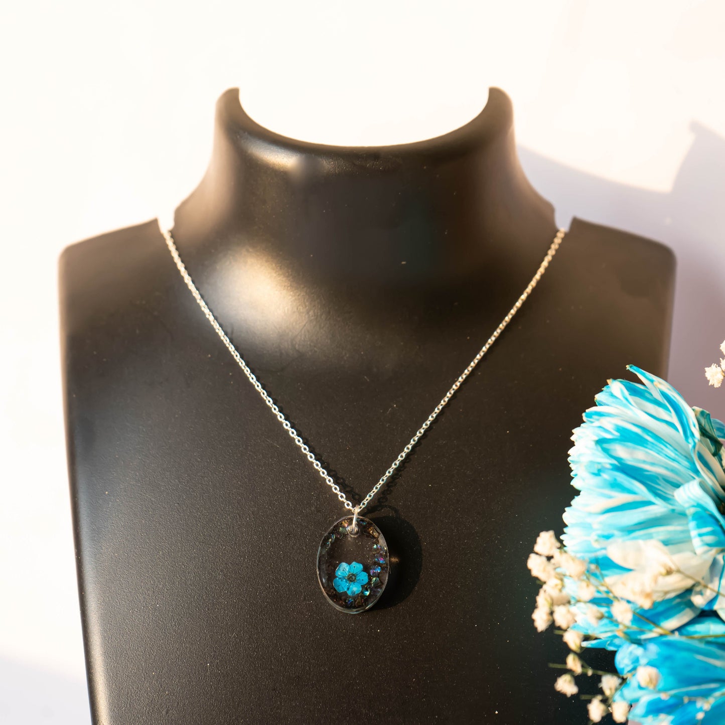 A collection of handmade resin art pendants, showcasing intricate floral designs preserved in clear resin, attached to delicate necklaces.