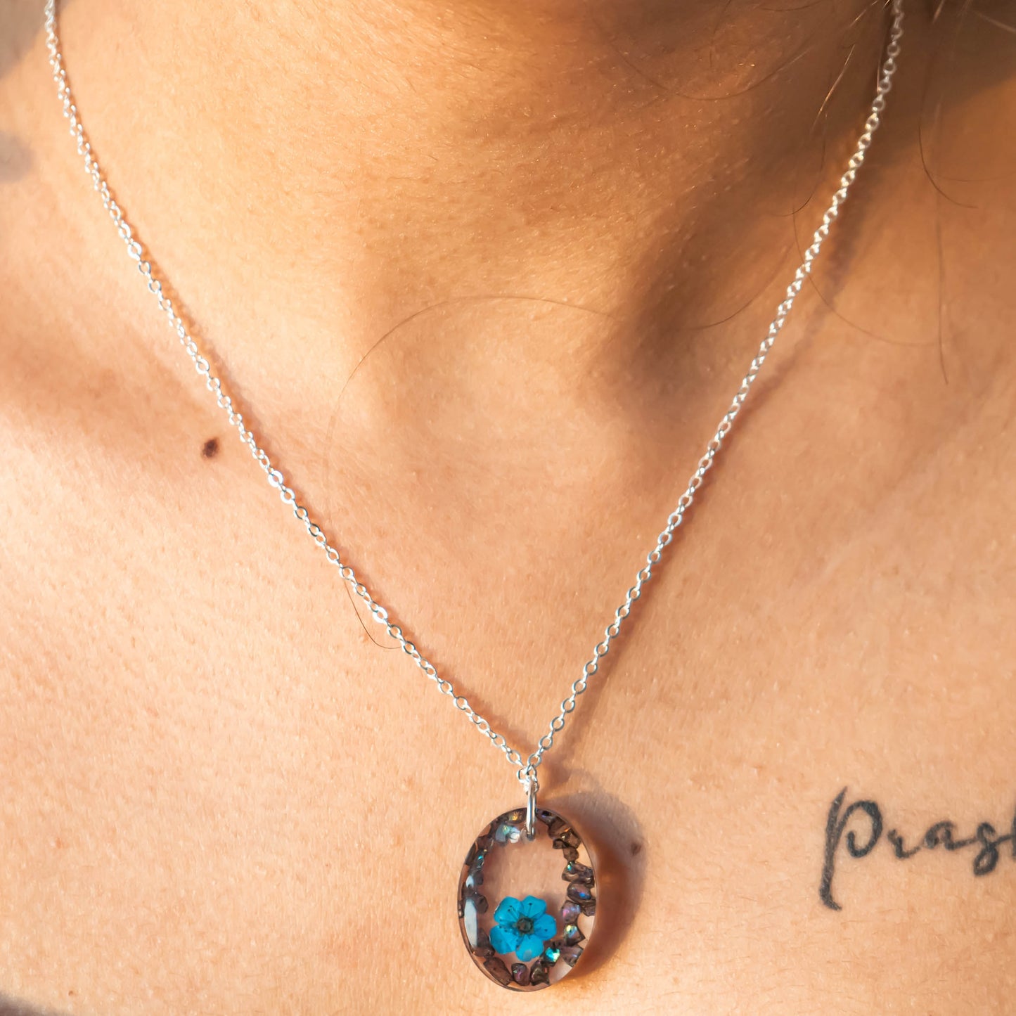 A collection of handmade resin art pendants, showcasing intricate floral designs preserved in clear resin, attached to delicate necklaces.