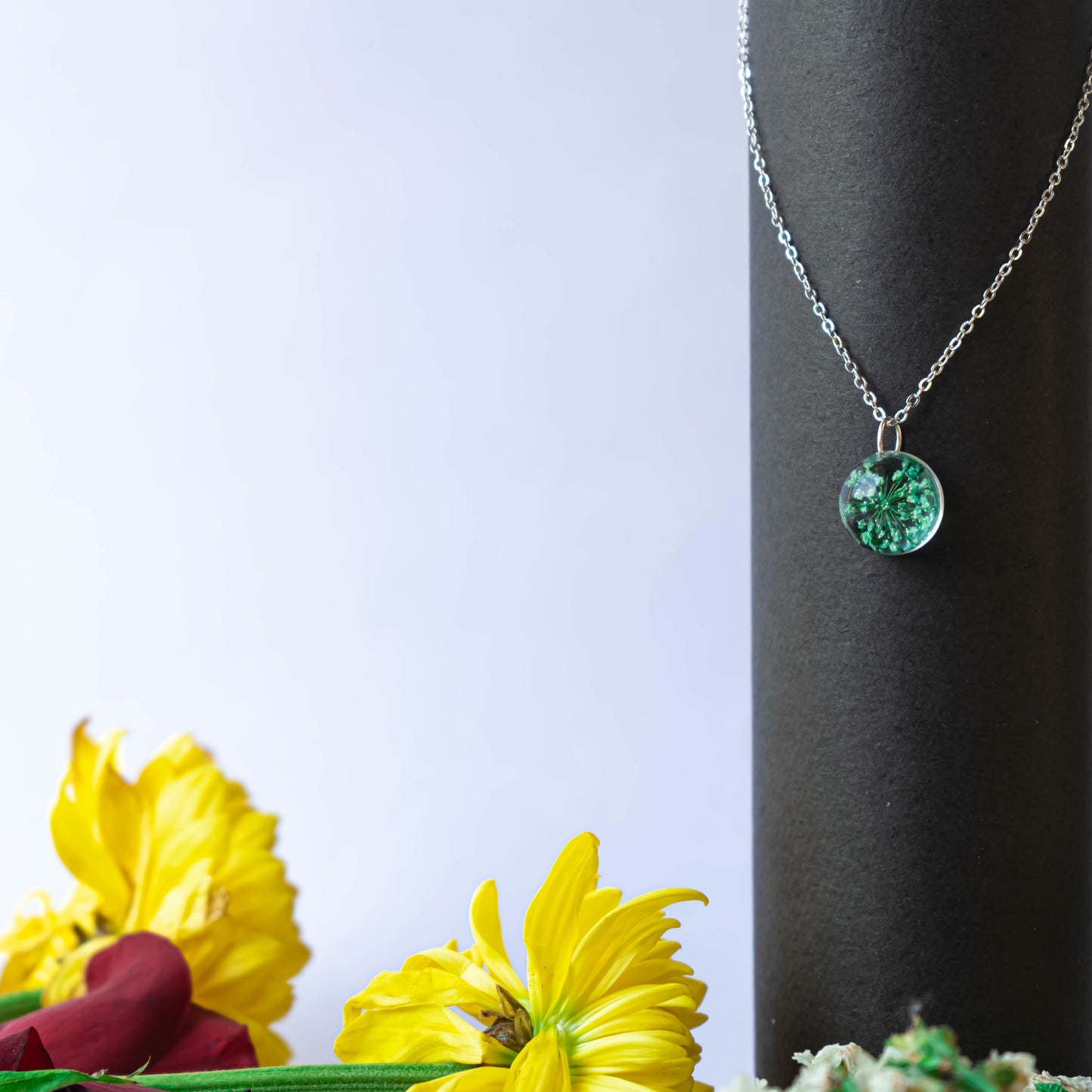 A collection of handmade resin art pendants, showcasing intricate floral designs preserved in clear resin, attached to delicate necklaces.