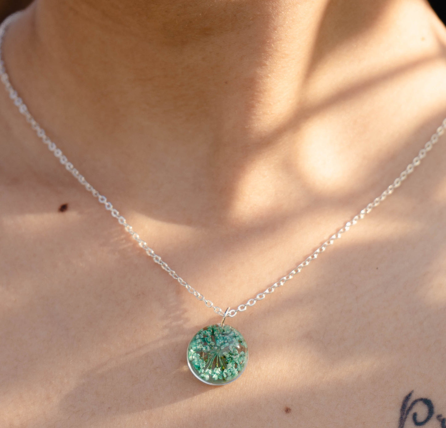 A collection of handmade resin art pendants, showcasing intricate floral designs preserved in clear resin, attached to delicate necklaces.