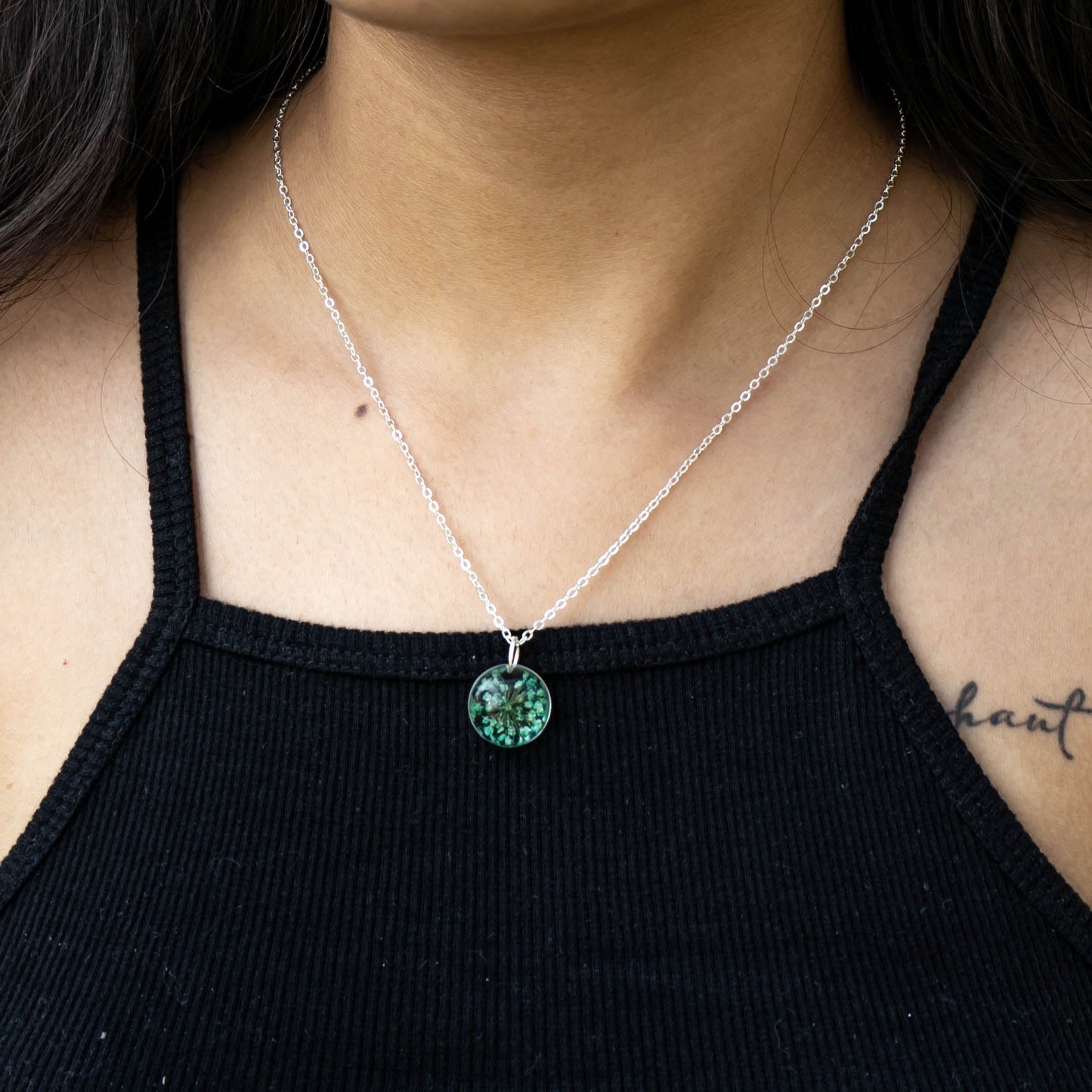 A collection of handmade resin art pendants, showcasing intricate floral designs preserved in clear resin, attached to delicate necklaces.