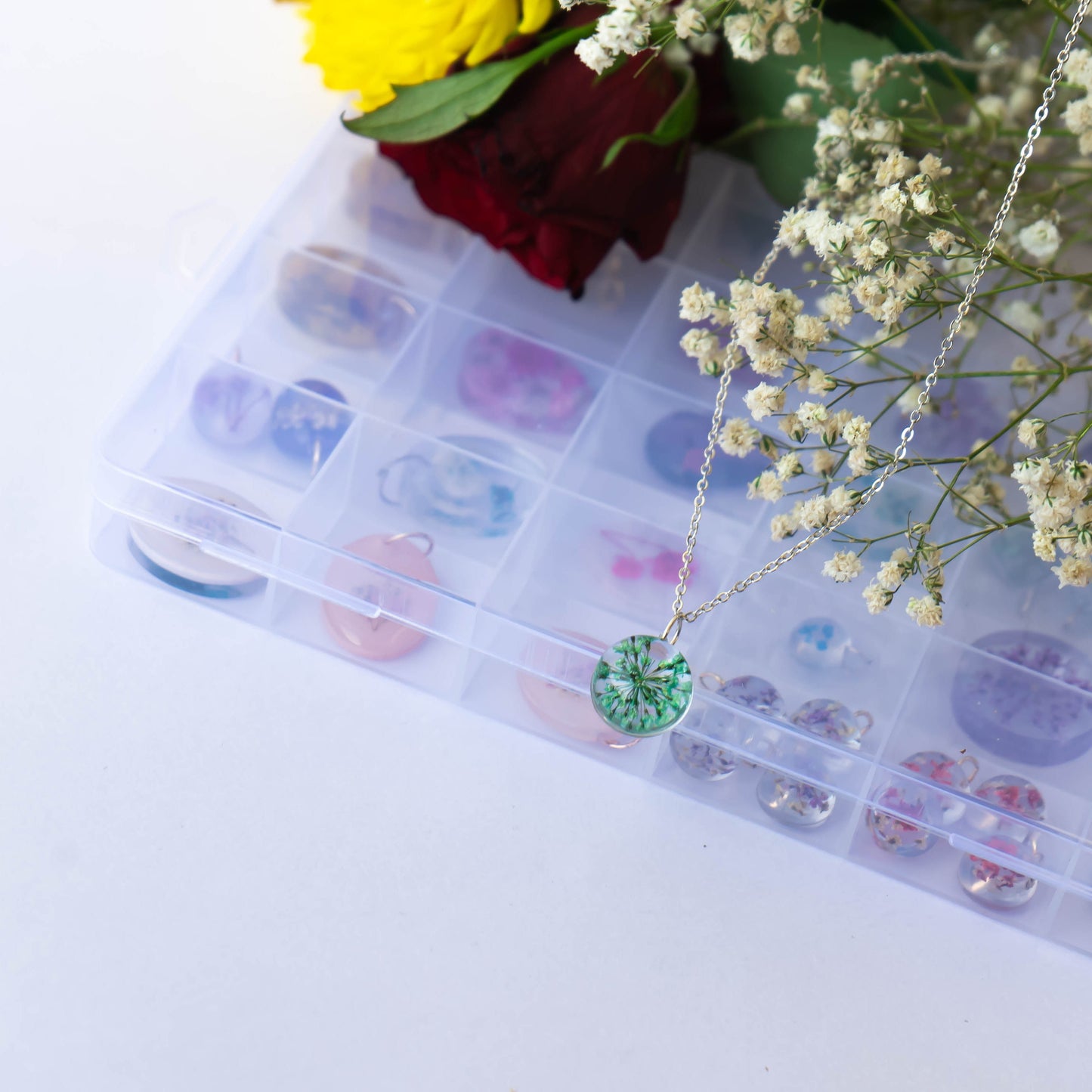 A collection of handmade resin art pendants, showcasing intricate floral designs preserved in clear resin, attached to delicate necklaces.