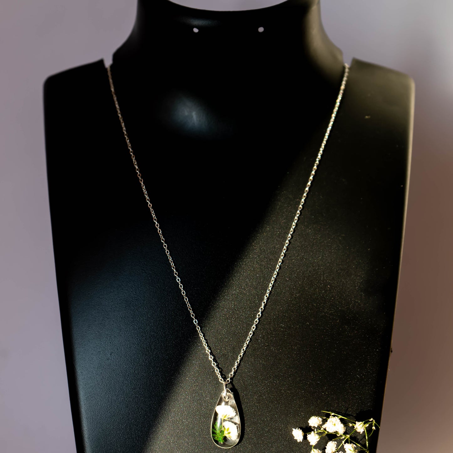 A collection of handmade resin art pendants, showcasing intricate floral designs preserved in clear resin, attached to delicate necklaces.