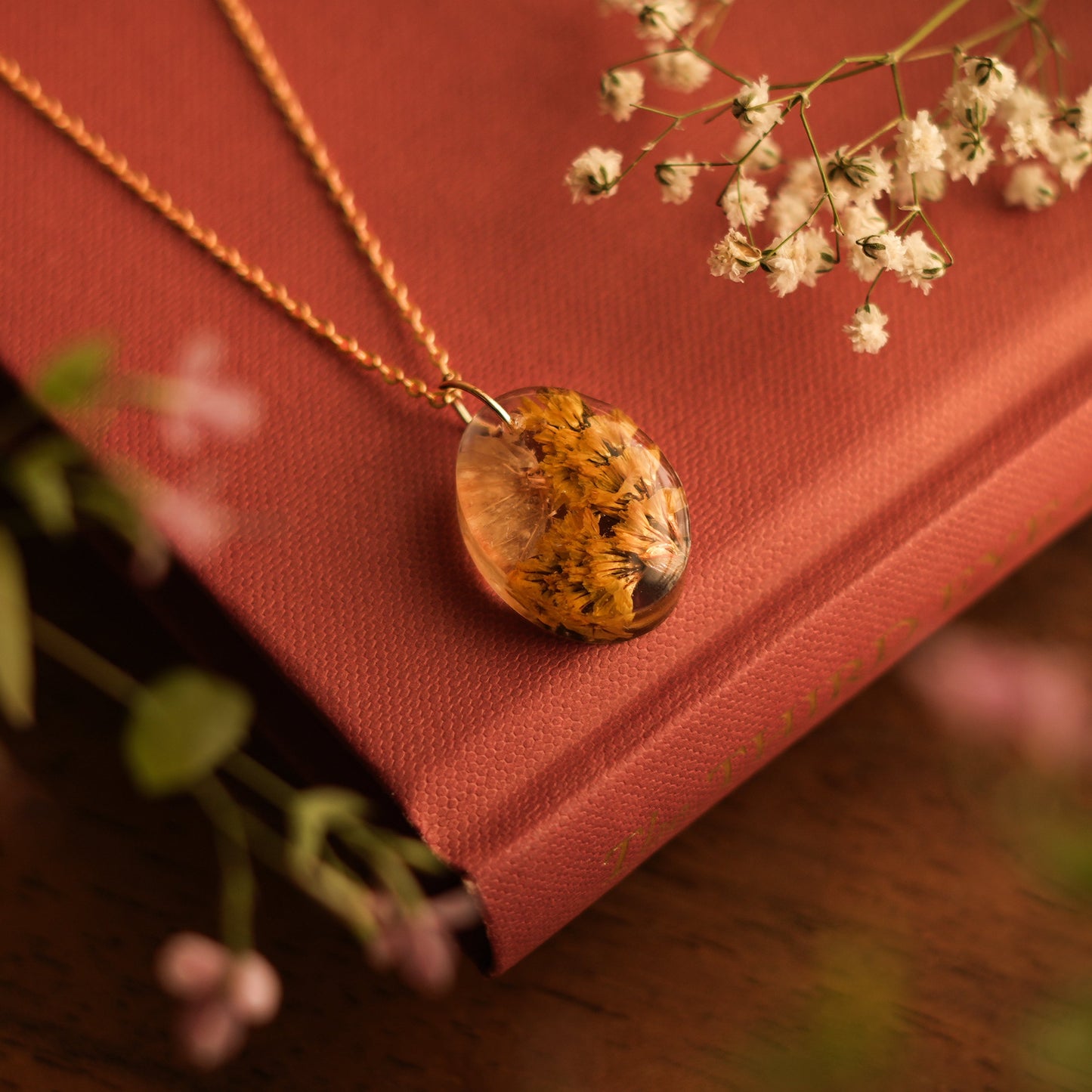 A collection of handmade resin art pendants, showcasing intricate floral designs preserved in clear resin, attached to delicate necklaces.
