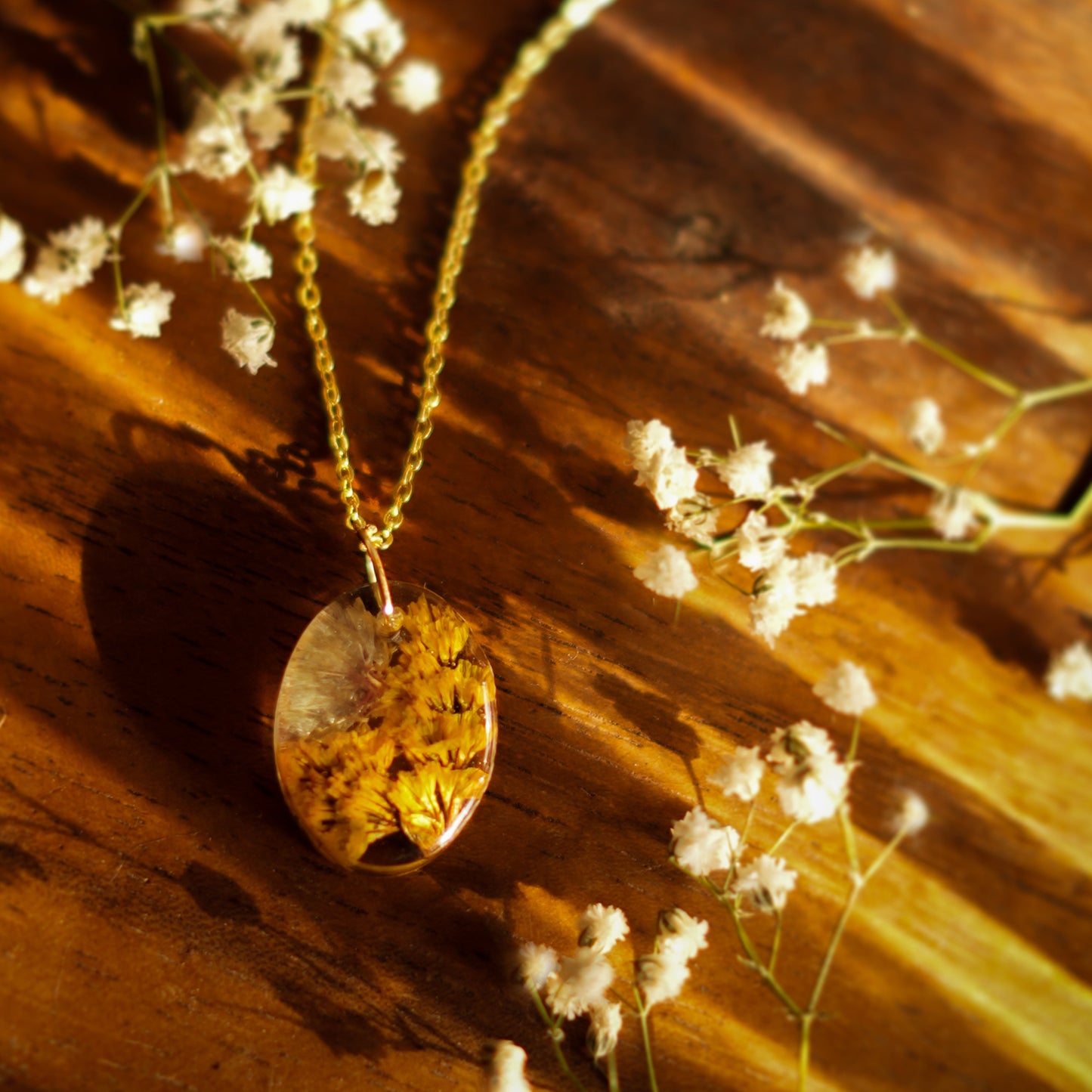 A collection of handmade resin art pendants, showcasing intricate floral designs preserved in clear resin, attached to delicate necklaces.