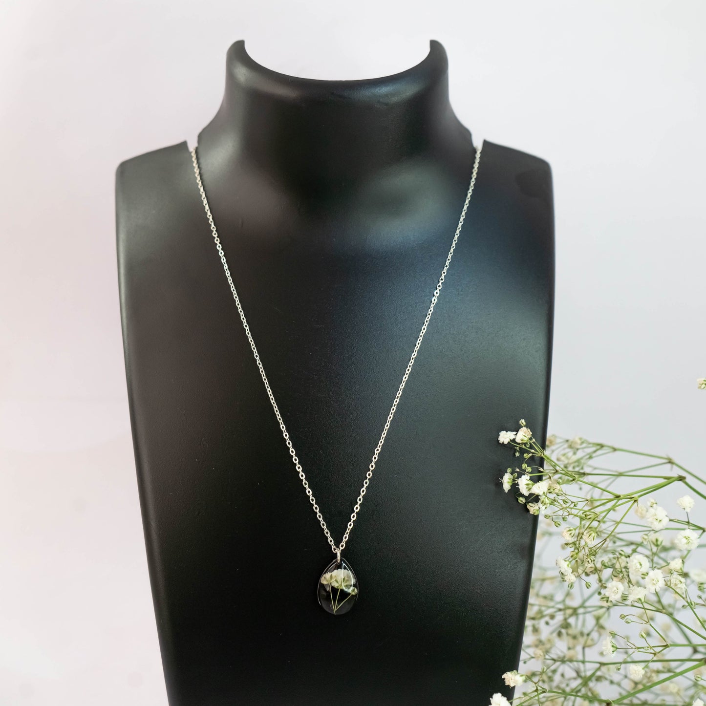 A collection of handmade resin art pendants, showcasing intricate floral designs preserved in clear resin, attached to delicate necklaces.