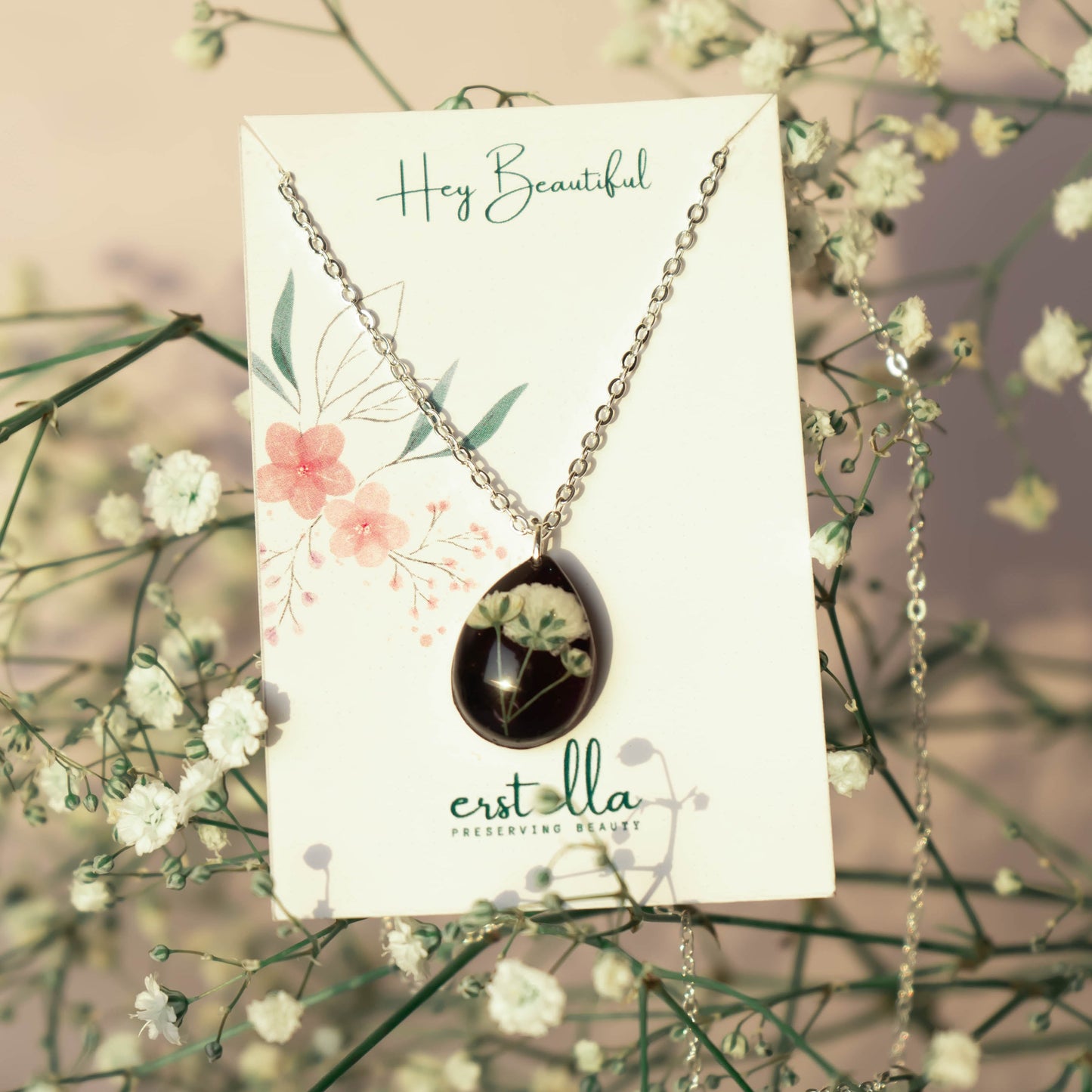 A collection of handmade resin art pendants, showcasing intricate floral designs preserved in clear resin, attached to delicate necklaces.