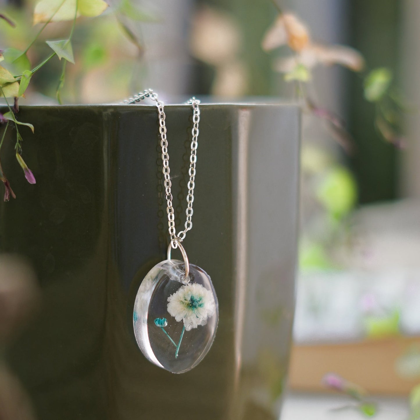 A collection of handmade resin art pendants, showcasing intricate floral designs preserved in clear resin, attached to delicate necklaces.