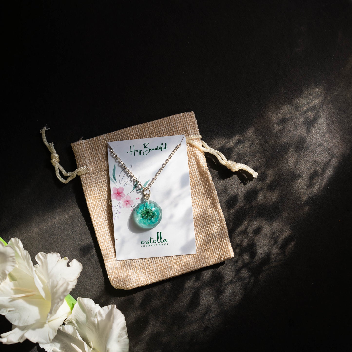 A collection of handmade resin art pendants, showcasing intricate floral designs preserved in clear resin, attached to delicate necklaces.