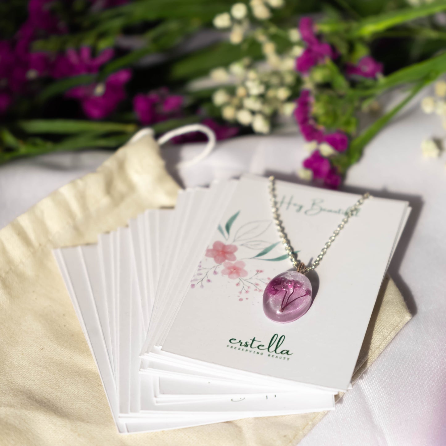 A collection of handmade resin art pendants, showcasing intricate floral designs preserved in clear resin, attached to delicate necklaces.