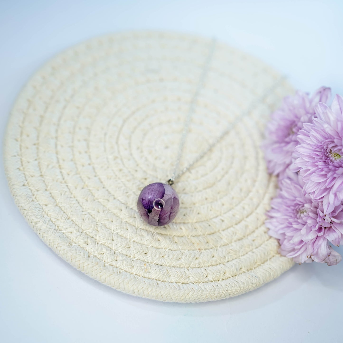 A collection of handmade resin art pendants, showcasing intricate floral designs preserved in clear resin, attached to delicate necklaces.