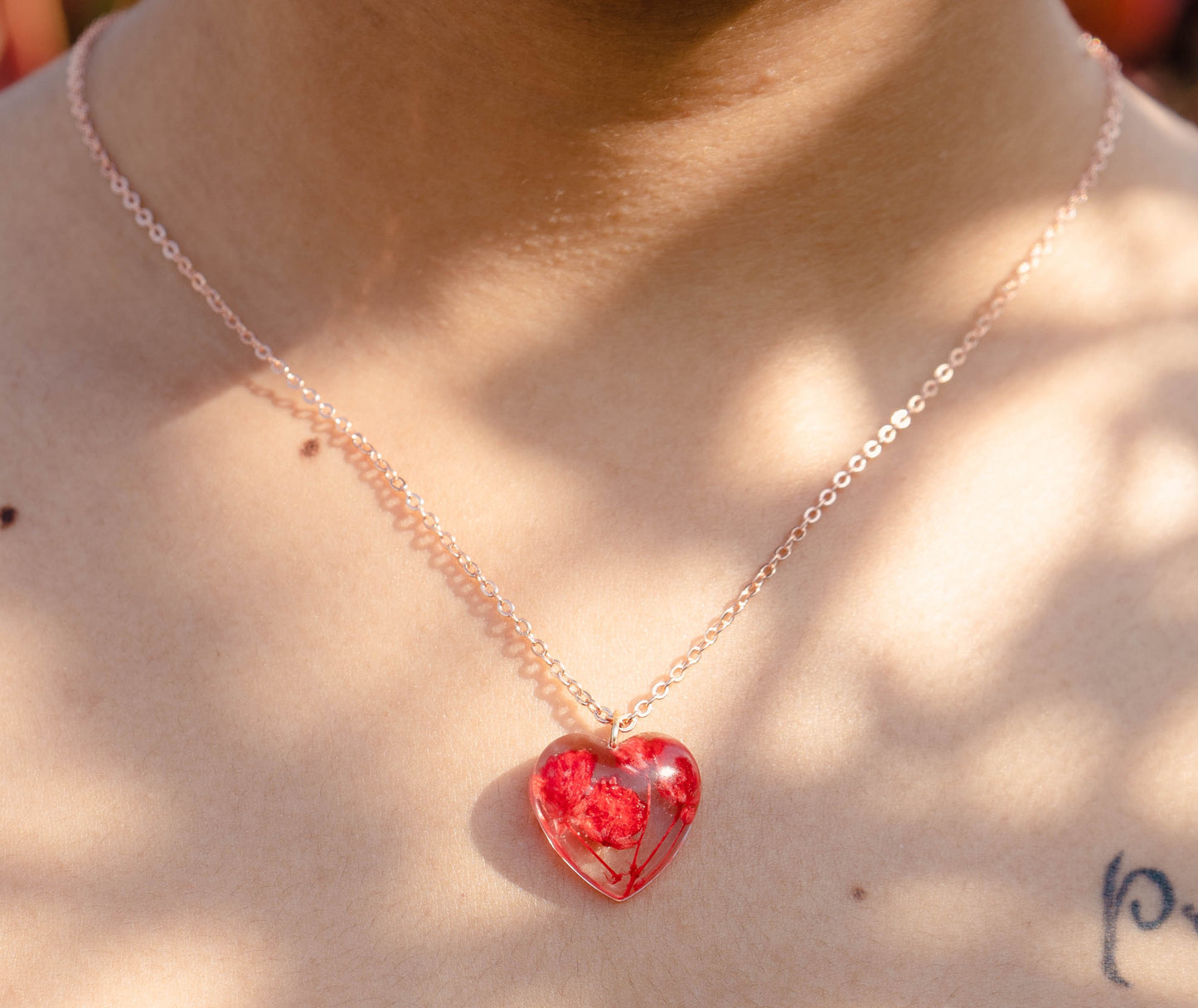 A collection of handmade resin art pendants, showcasing intricate floral designs preserved in clear resin, attached to delicate necklaces.