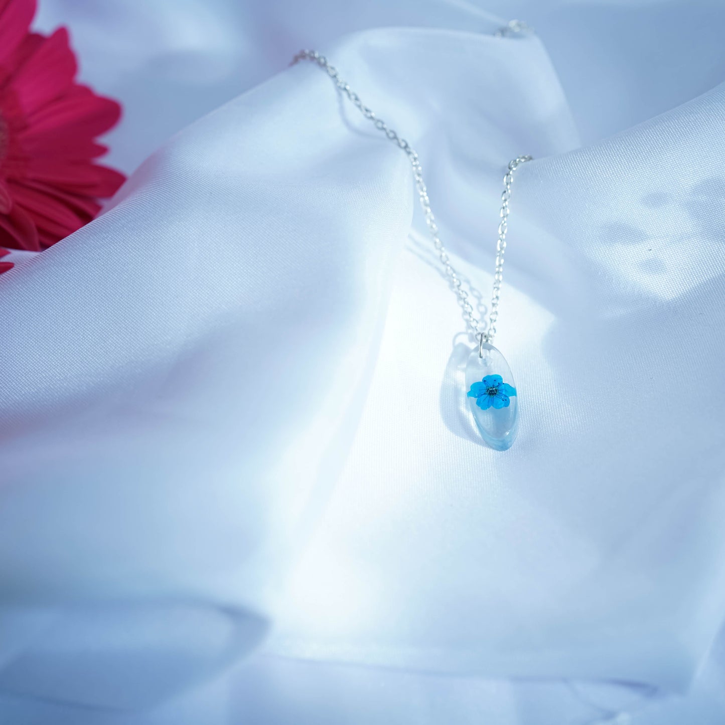 A collection of handmade resin art pendants, showcasing intricate floral designs preserved in clear resin, attached to delicate necklaces.