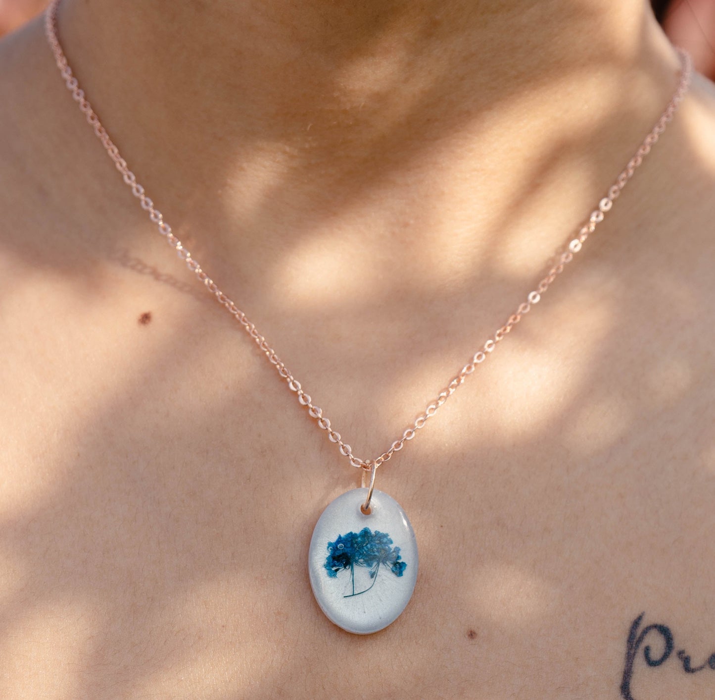 A collection of handmade resin art pendants, showcasing intricate floral designs preserved in clear resin, attached to delicate necklaces.