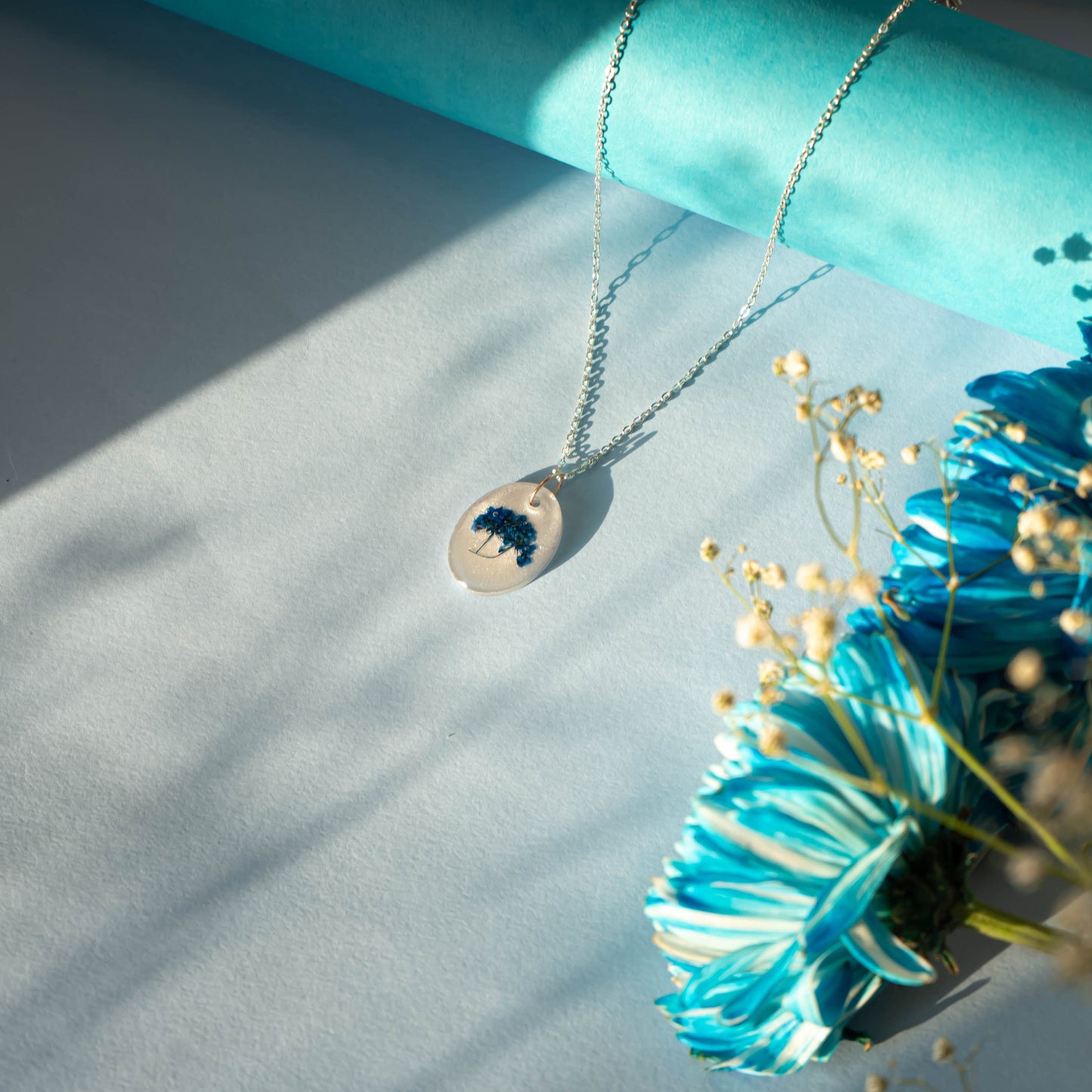 A collection of handmade resin art pendants, showcasing intricate floral designs preserved in clear resin, attached to delicate necklaces.