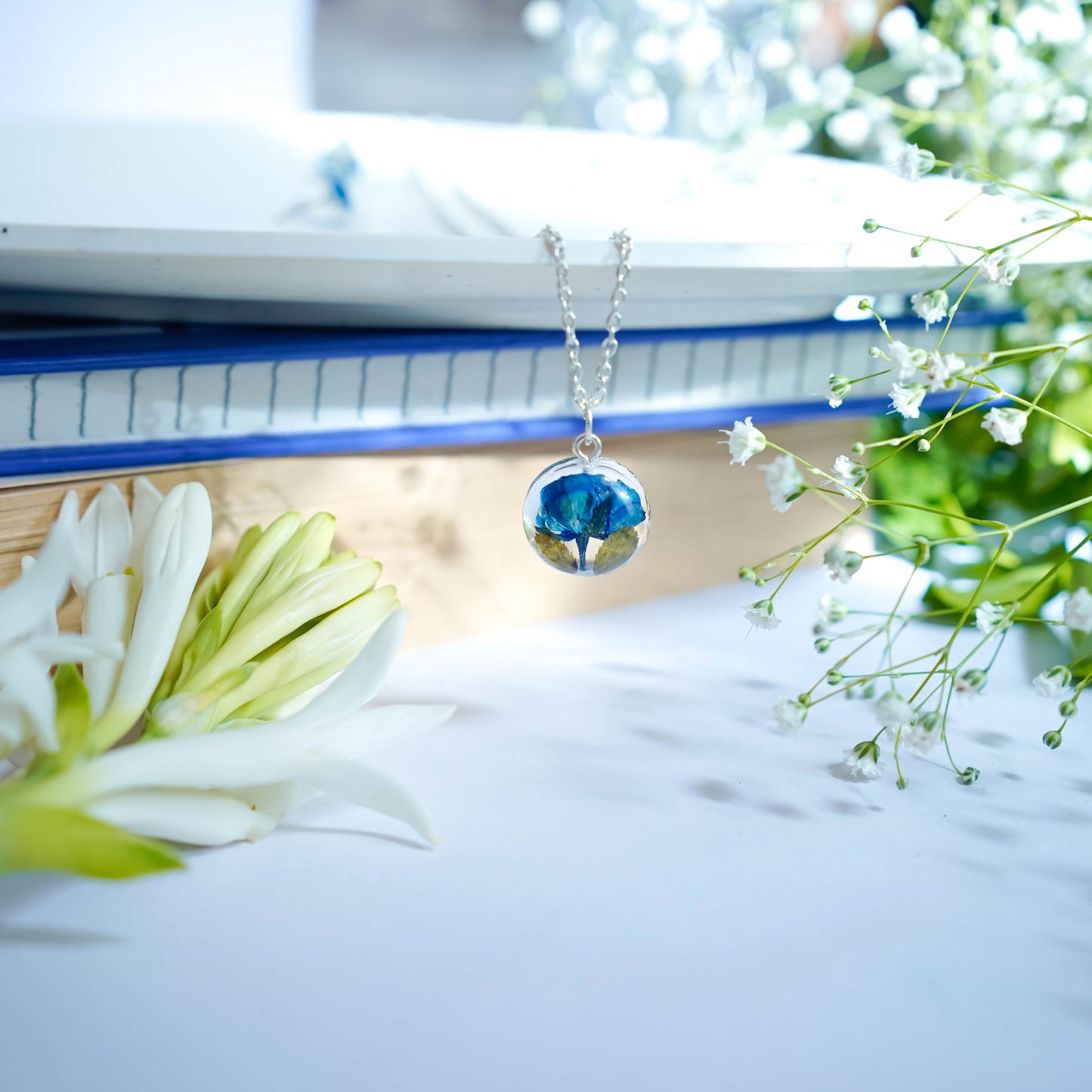 A collection of handmade resin art pendants, showcasing intricate floral designs preserved in clear resin, attached to delicate necklaces.