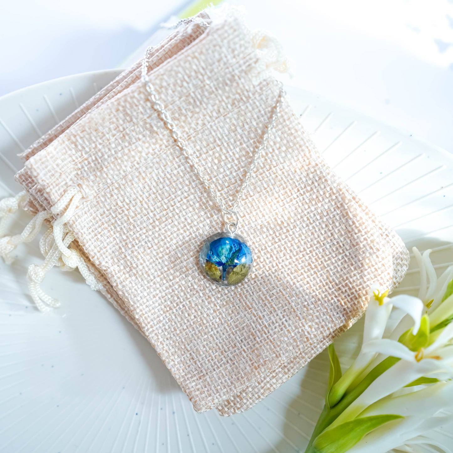 A collection of handmade resin art pendants, showcasing intricate floral designs preserved in clear resin, attached to delicate necklaces.