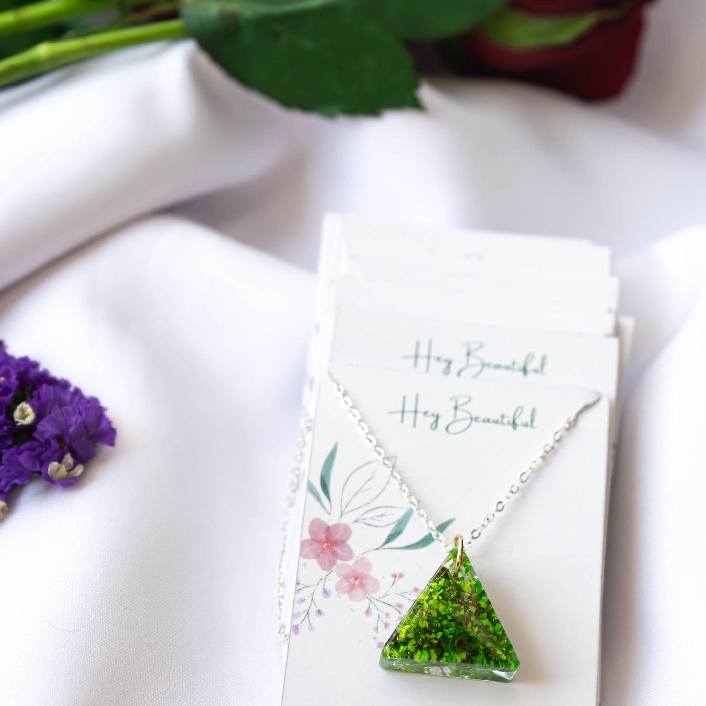 A collection of handmade resin art pendants, showcasing intricate floral designs preserved in clear resin, attached to delicate necklaces.