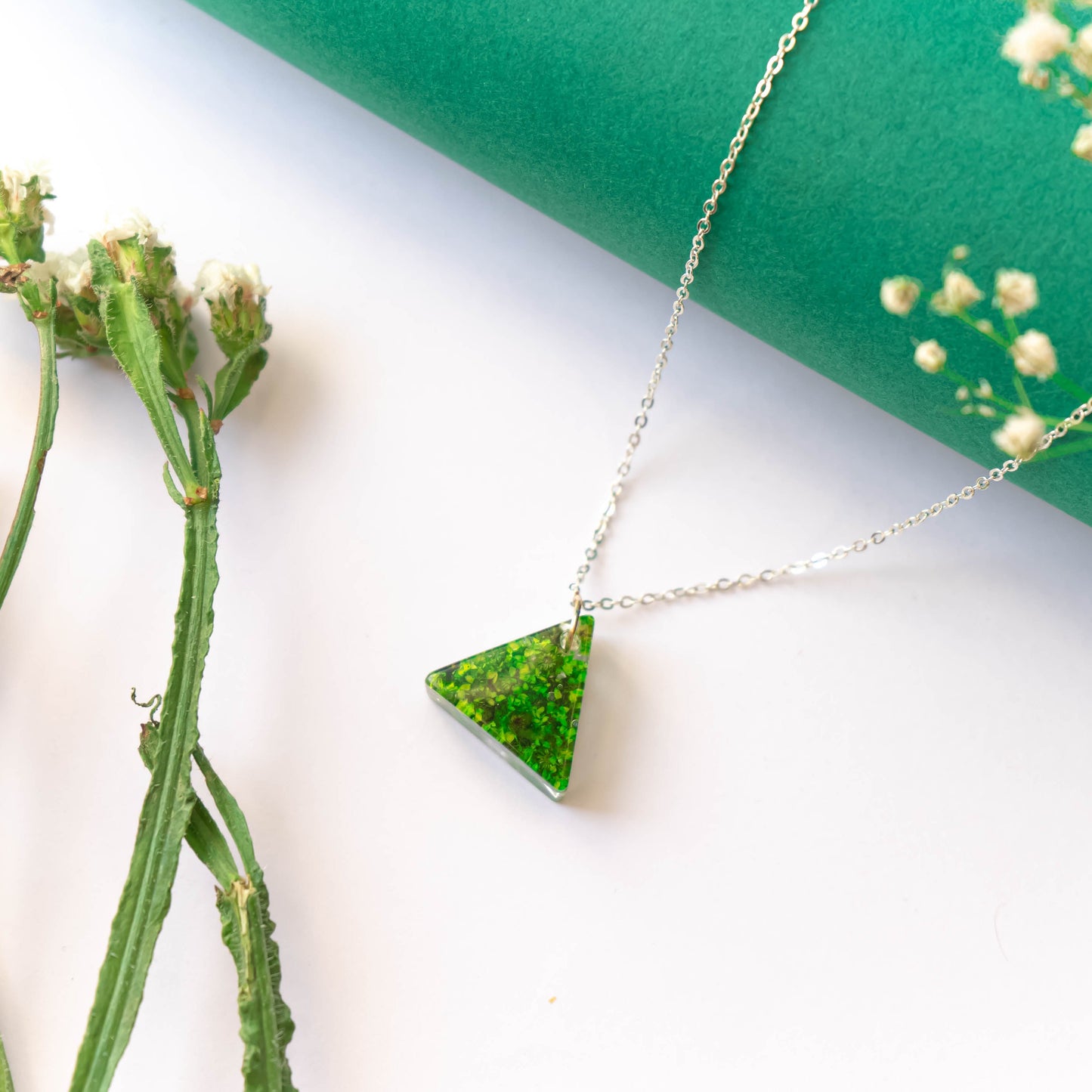 A collection of handmade resin art pendants, showcasing intricate floral designs preserved in clear resin, attached to delicate necklaces.