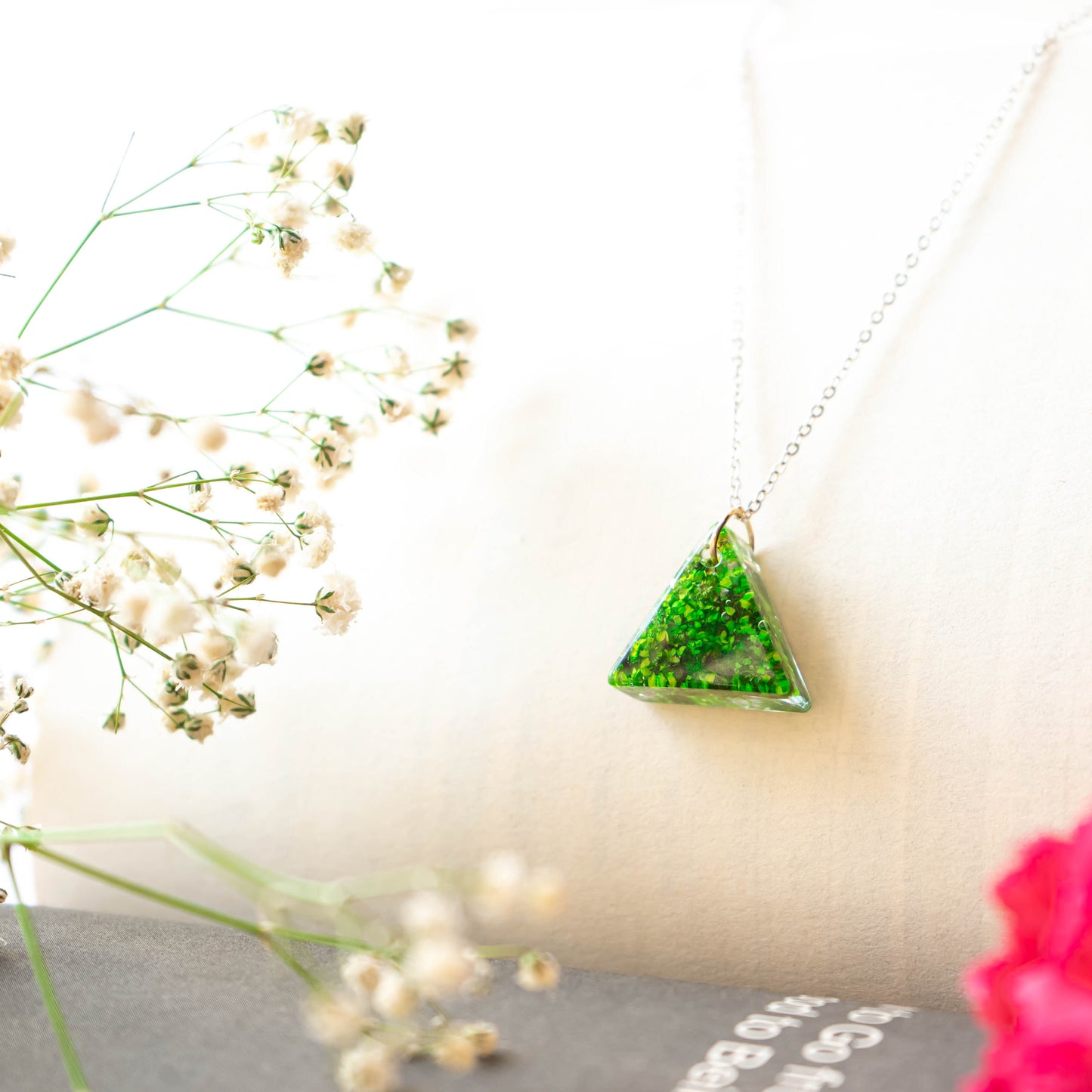 A collection of handmade resin art pendants, showcasing intricate floral designs preserved in clear resin, attached to delicate necklaces.