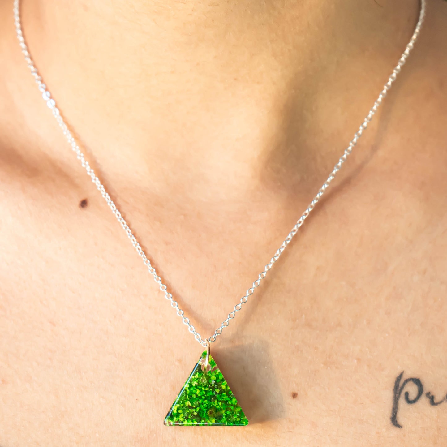 A collection of handmade resin art pendants, showcasing intricate floral designs preserved in clear resin, attached to delicate necklaces.