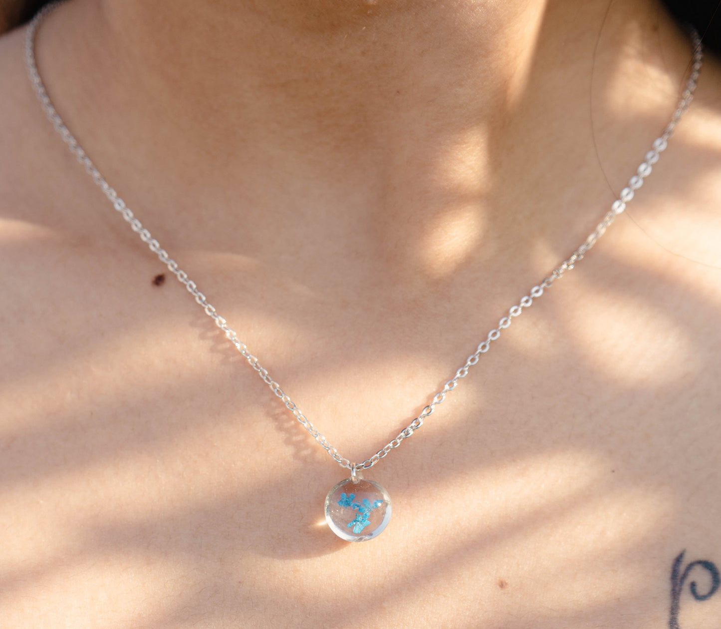 A collection of handmade resin art pendants, showcasing intricate floral designs preserved in clear resin, attached to delicate necklaces.