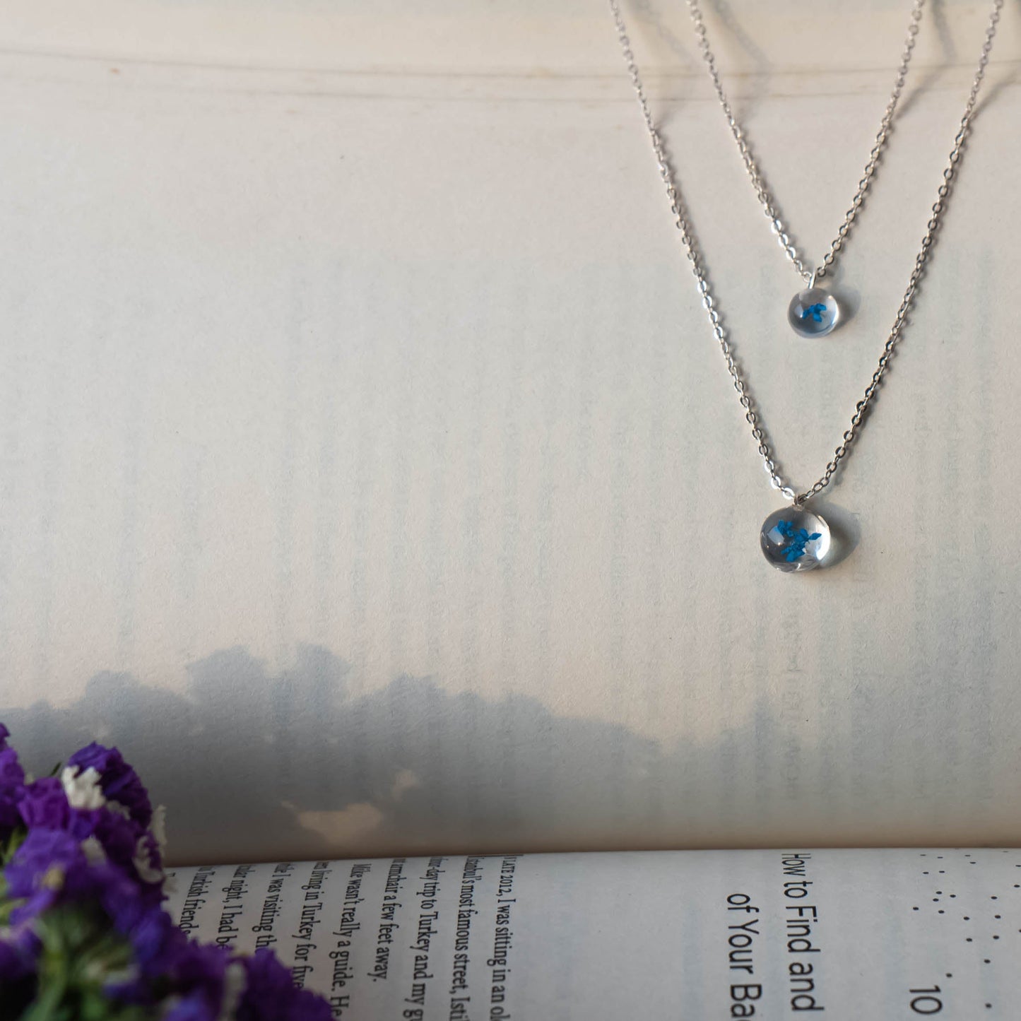 A collection of handmade resin art pendants, showcasing intricate floral designs preserved in clear resin, attached to delicate necklaces.