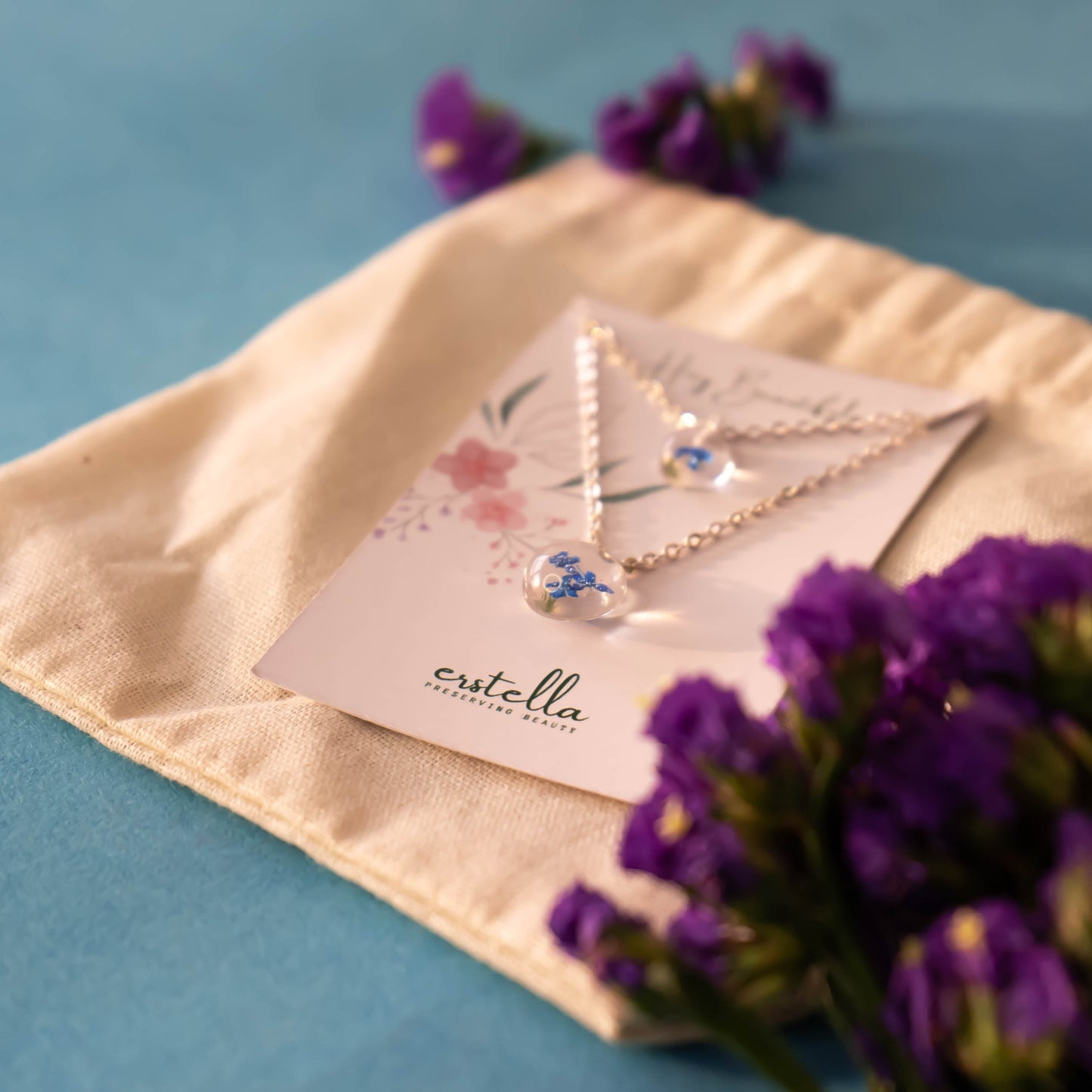 A collection of handmade resin art pendants, showcasing intricate floral designs preserved in clear resin, attached to delicate necklaces.