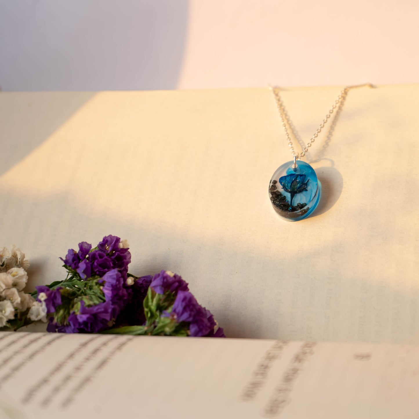 A collection of handmade resin art pendants, showcasing intricate floral designs preserved in clear resin, attached to delicate necklaces.