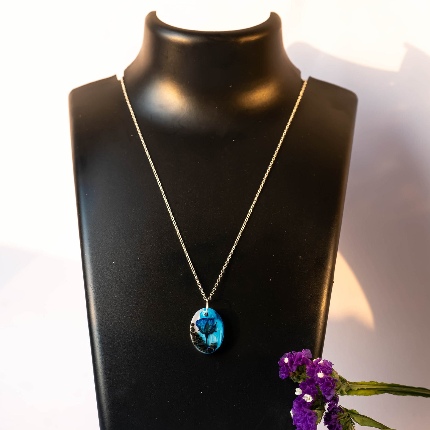 A collection of handmade resin art pendants, showcasing intricate floral designs preserved in clear resin, attached to delicate necklaces.