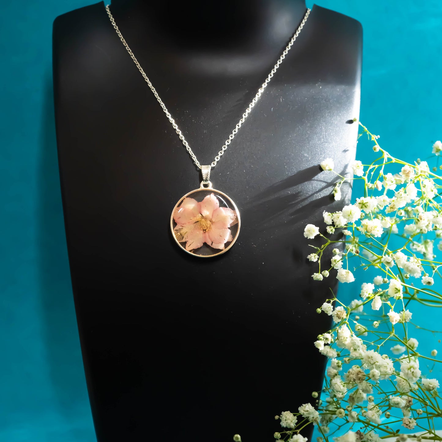 A collection of handmade resin art pendants, showcasing intricate floral designs preserved in clear resin, attached to delicate necklaces.