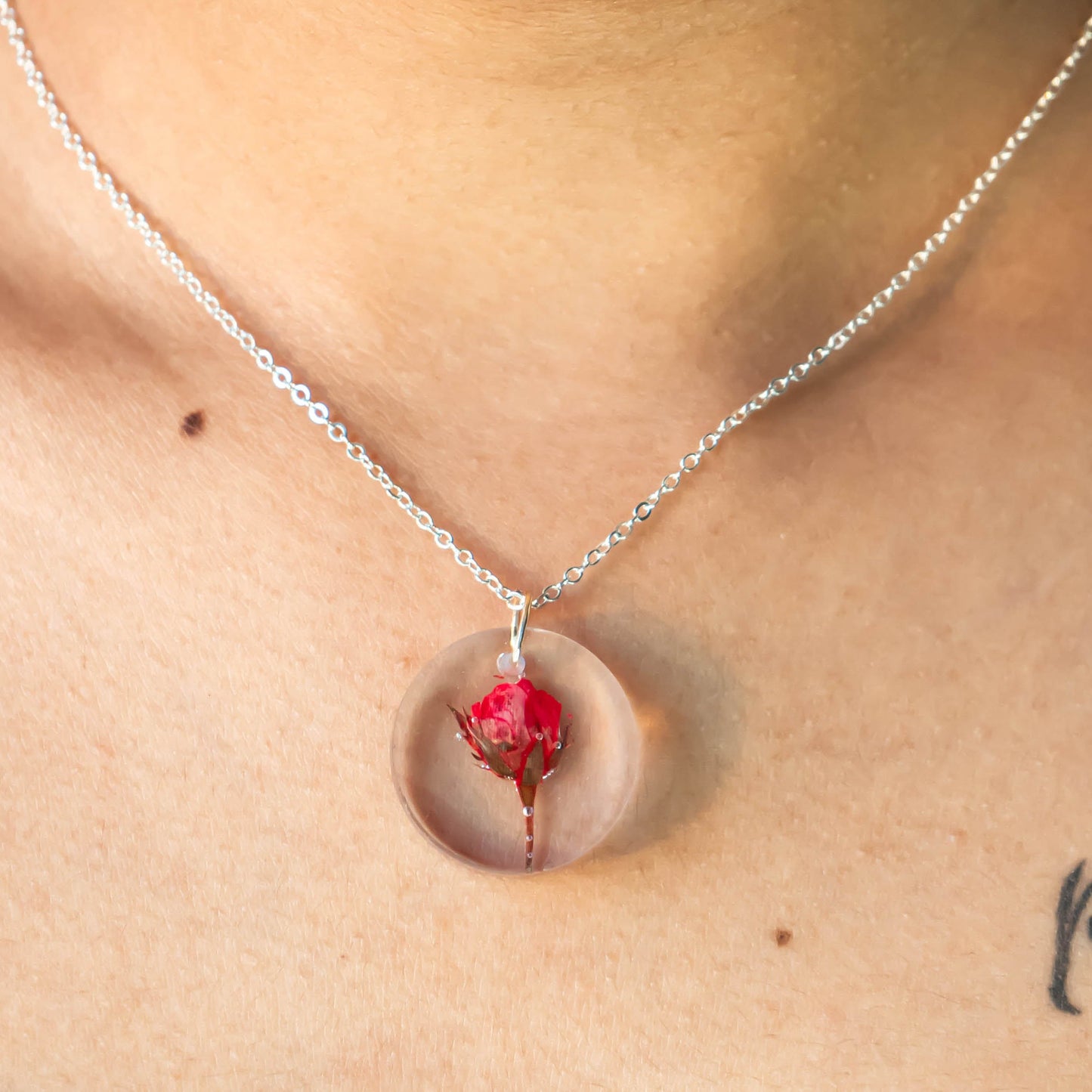 A collection of handmade resin art pendants, showcasing intricate floral designs preserved in clear resin, attached to delicate necklaces.