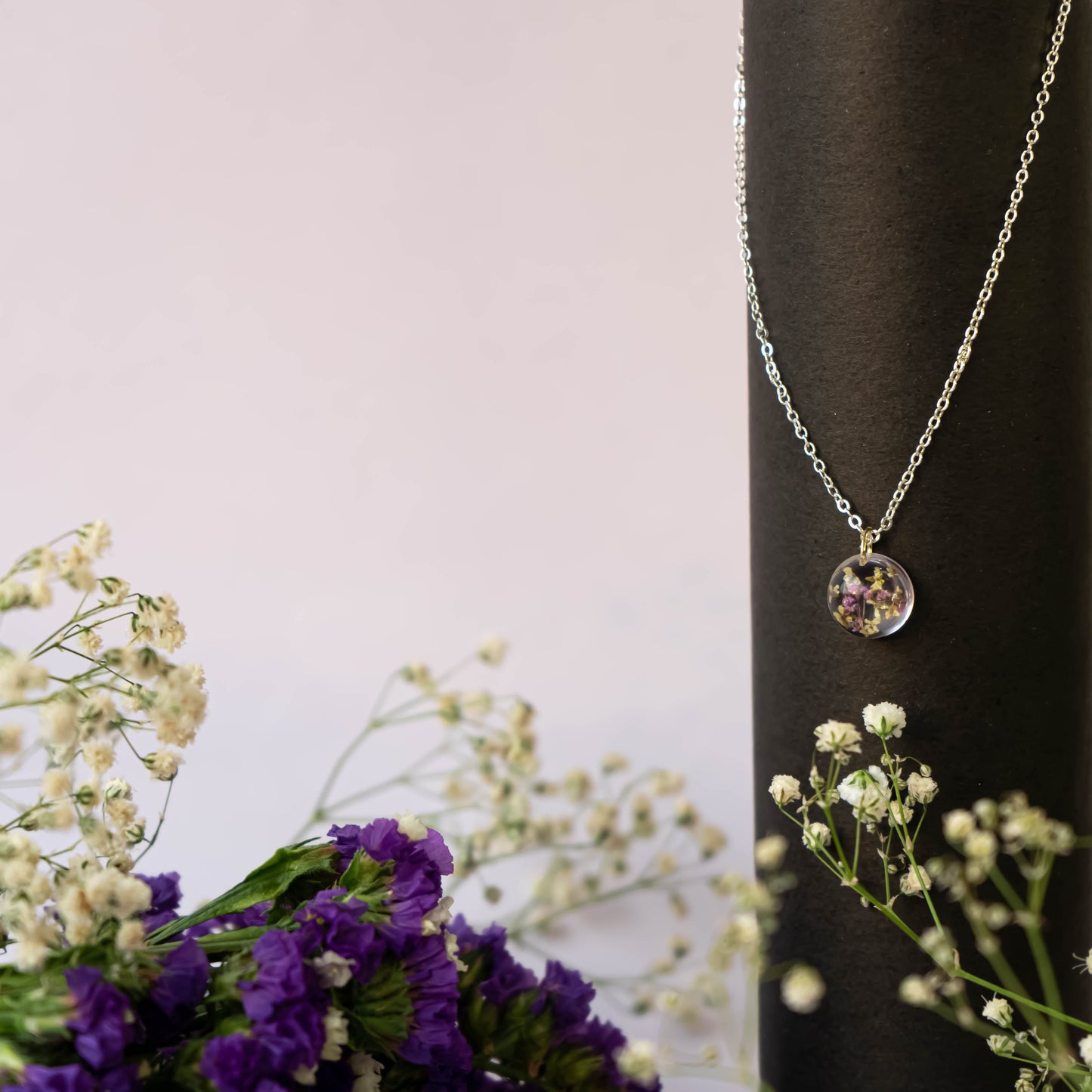 A collection of handmade resin art pendants, showcasing intricate floral designs preserved in clear resin, attached to delicate necklaces.