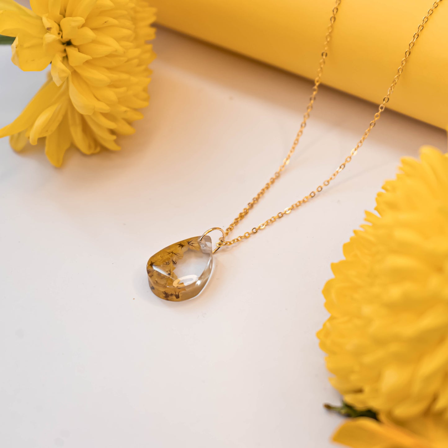 A collection of handmade resin art pendants, showcasing intricate floral designs preserved in clear resin, attached to delicate necklaces.