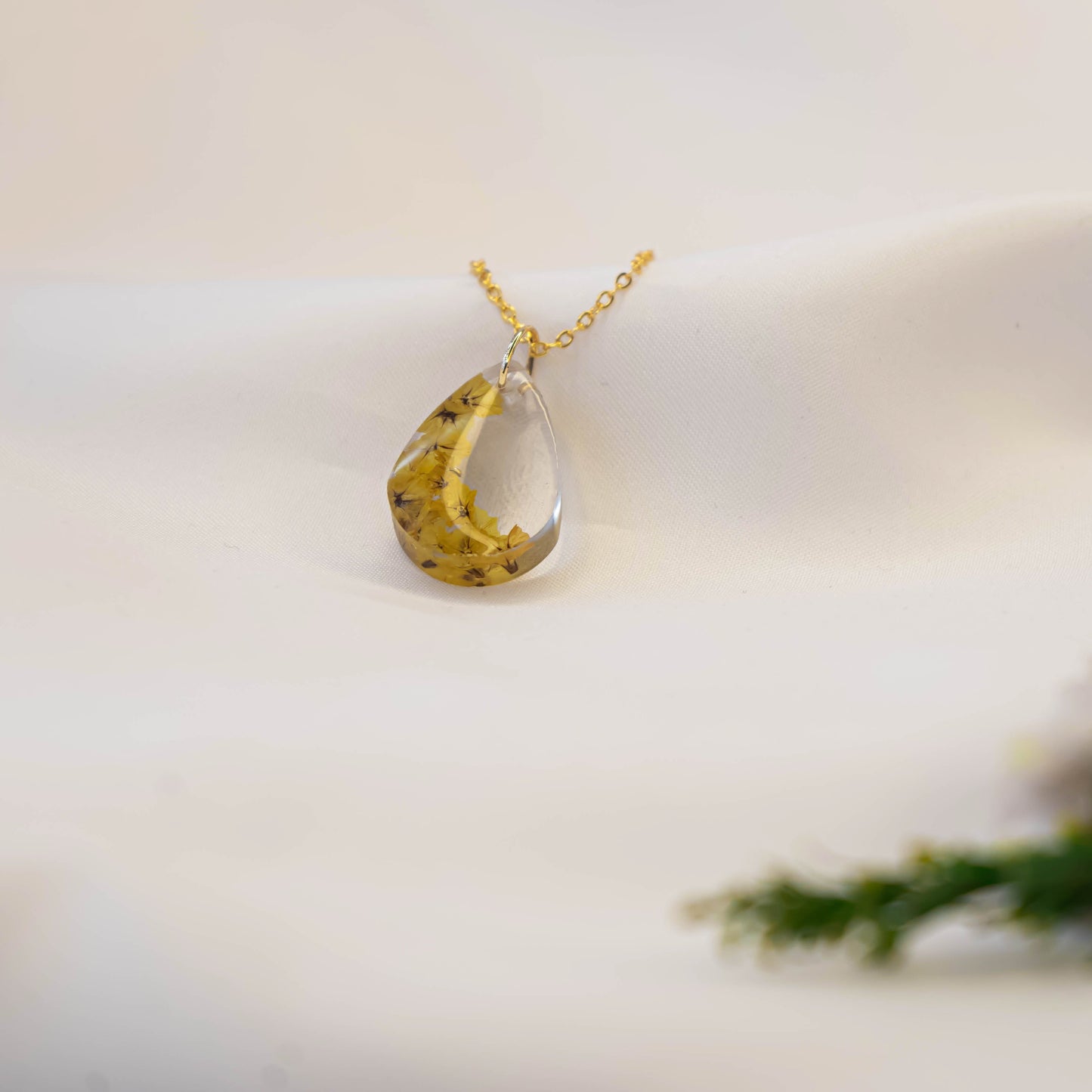 A collection of handmade resin art pendants, showcasing intricate floral designs preserved in clear resin, attached to delicate necklaces.