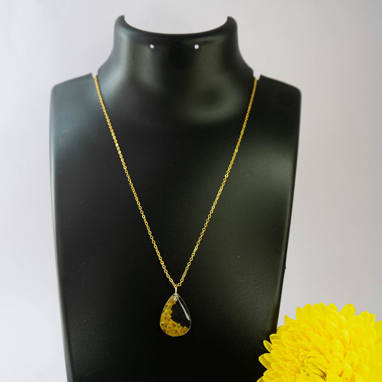 A collection of handmade resin art pendants, showcasing intricate floral designs preserved in clear resin, attached to delicate necklaces.