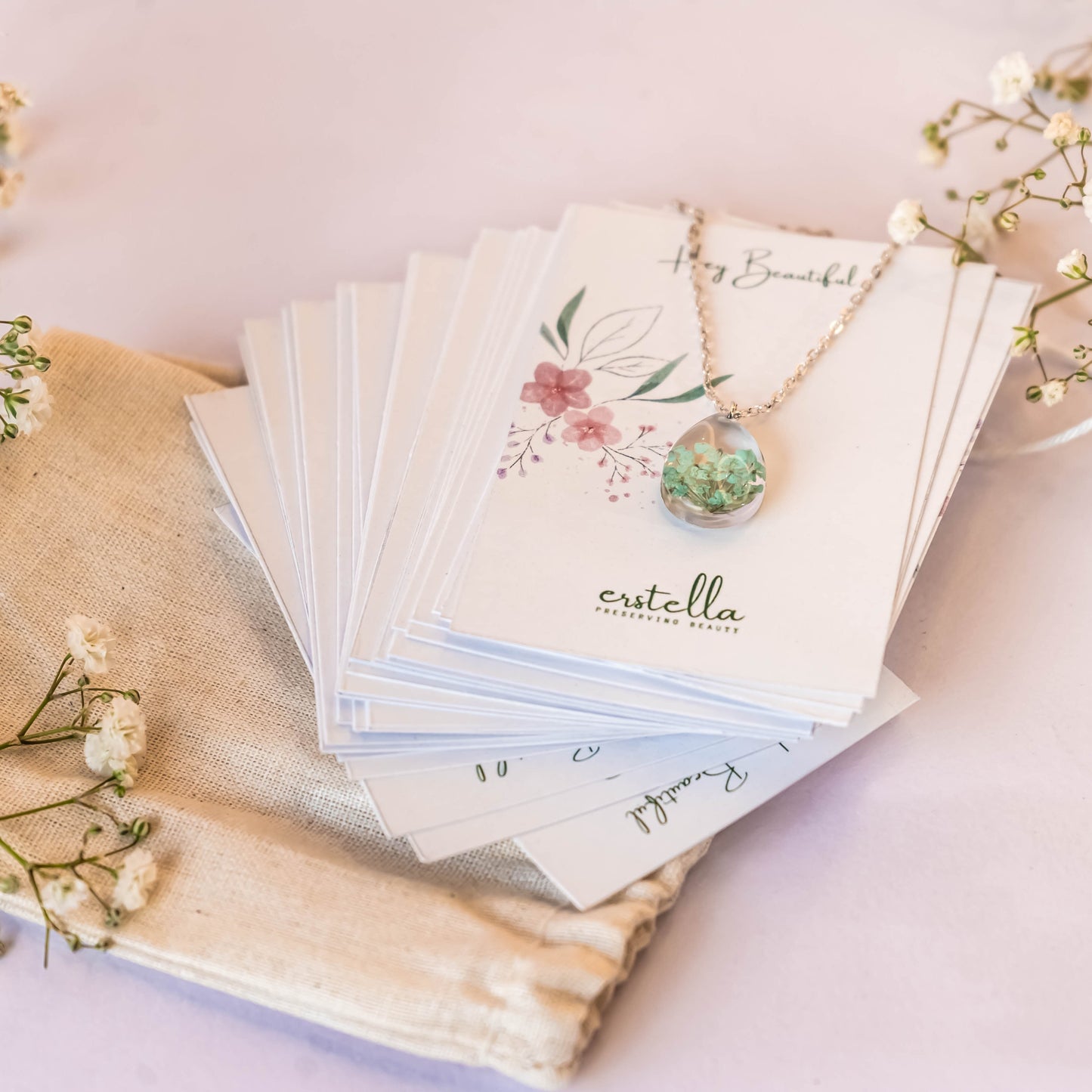 A collection of handmade resin art pendants, showcasing intricate floral designs preserved in clear resin, attached to delicate necklaces.